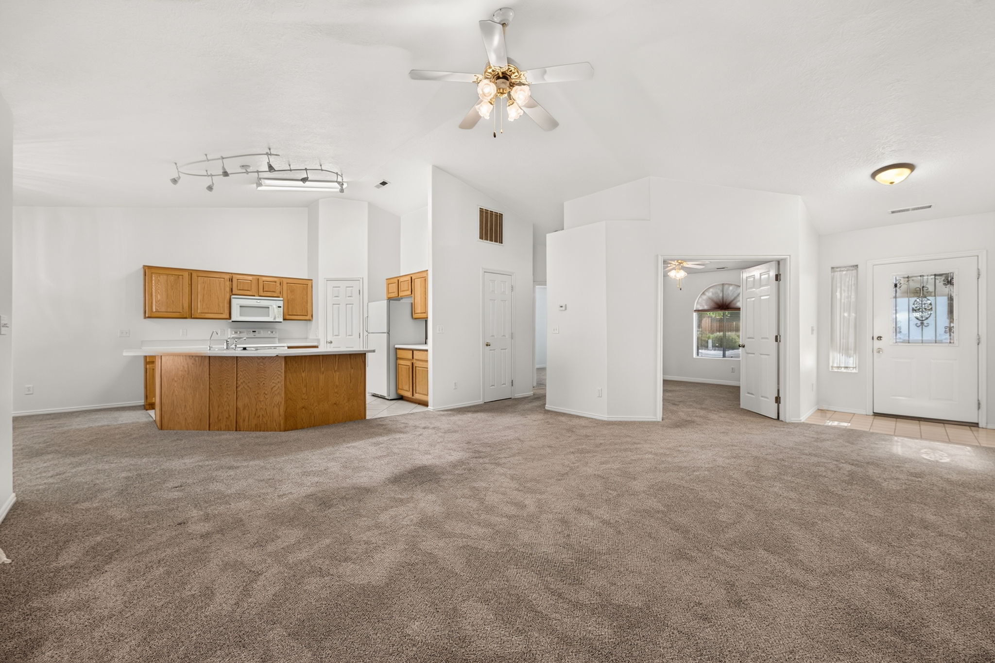 Spacious interior featuring vaulted ceilings and a combination of carpet and tile flooring
