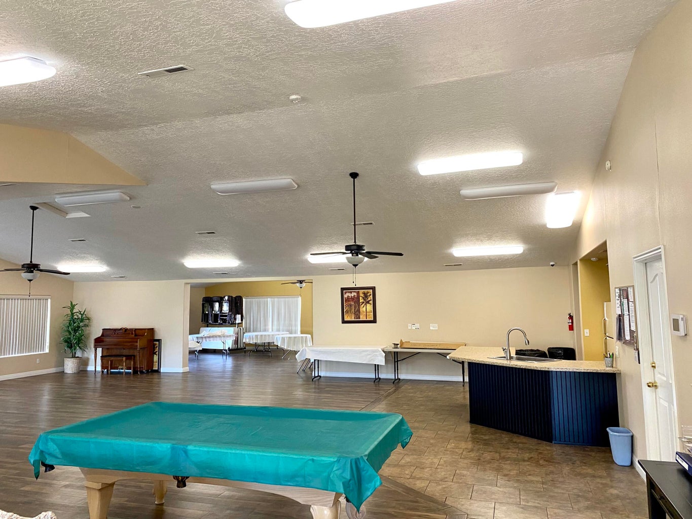Expansive open-concept room featuring wood-finish flooring, recessed ceiling lighting, and multiple ceiling fans
