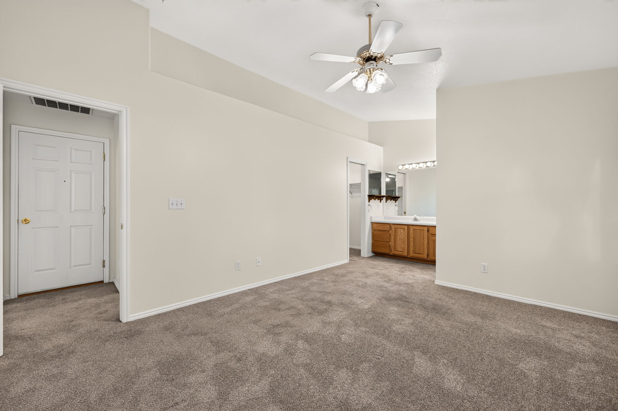 Spacious interior room featuring plush carpet flooring and a ceiling fan with integrated lighting