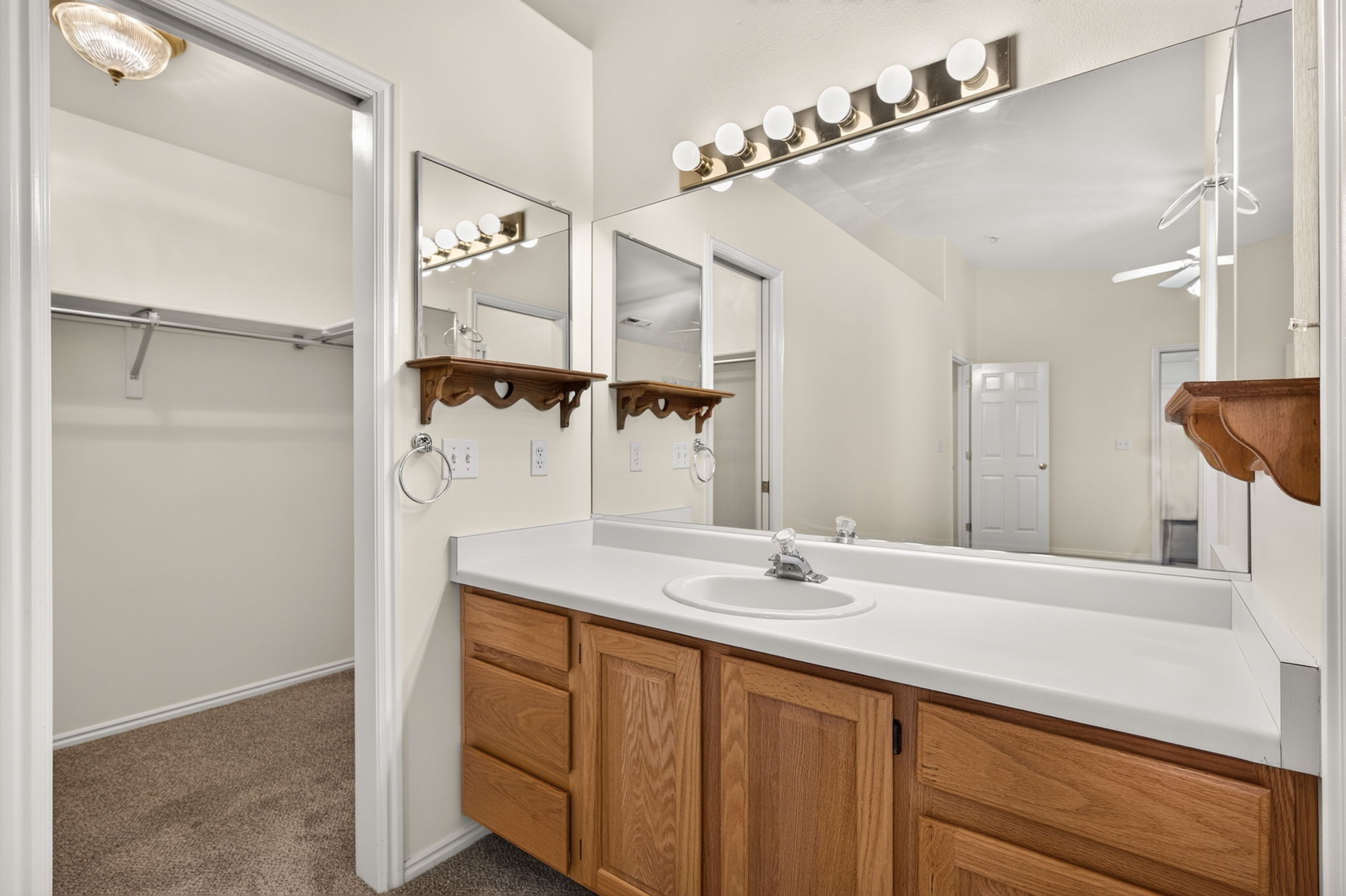 Bathroom vanity featuring a single basin sink, white countertop, and wood-finish cabinetry