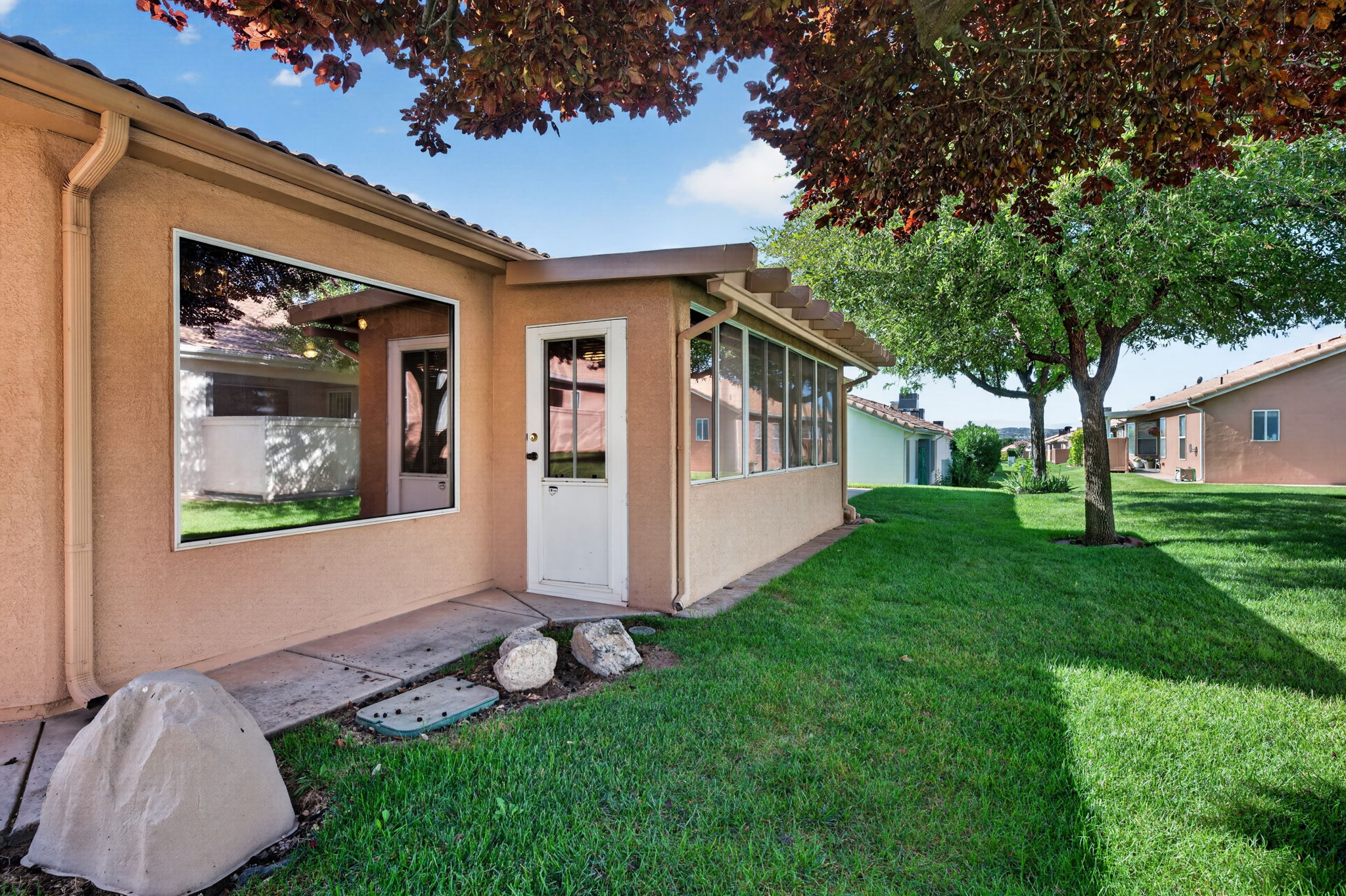 Tiled roofline above a stucco exterior featuring a large reflective window and a white paneled door