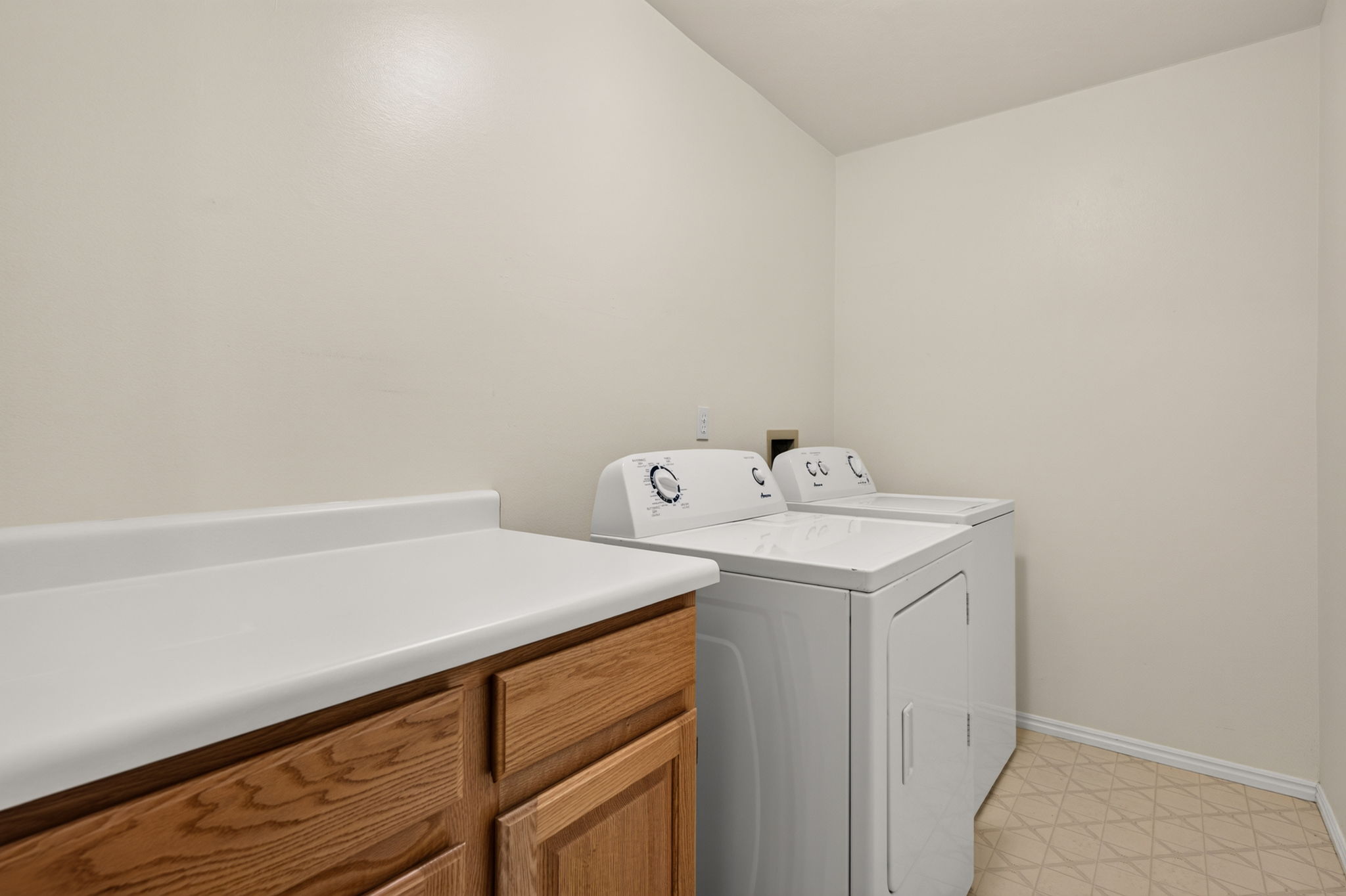 Dedicated utility area featuring wood cabinetry, white countertop, and tiled flooring