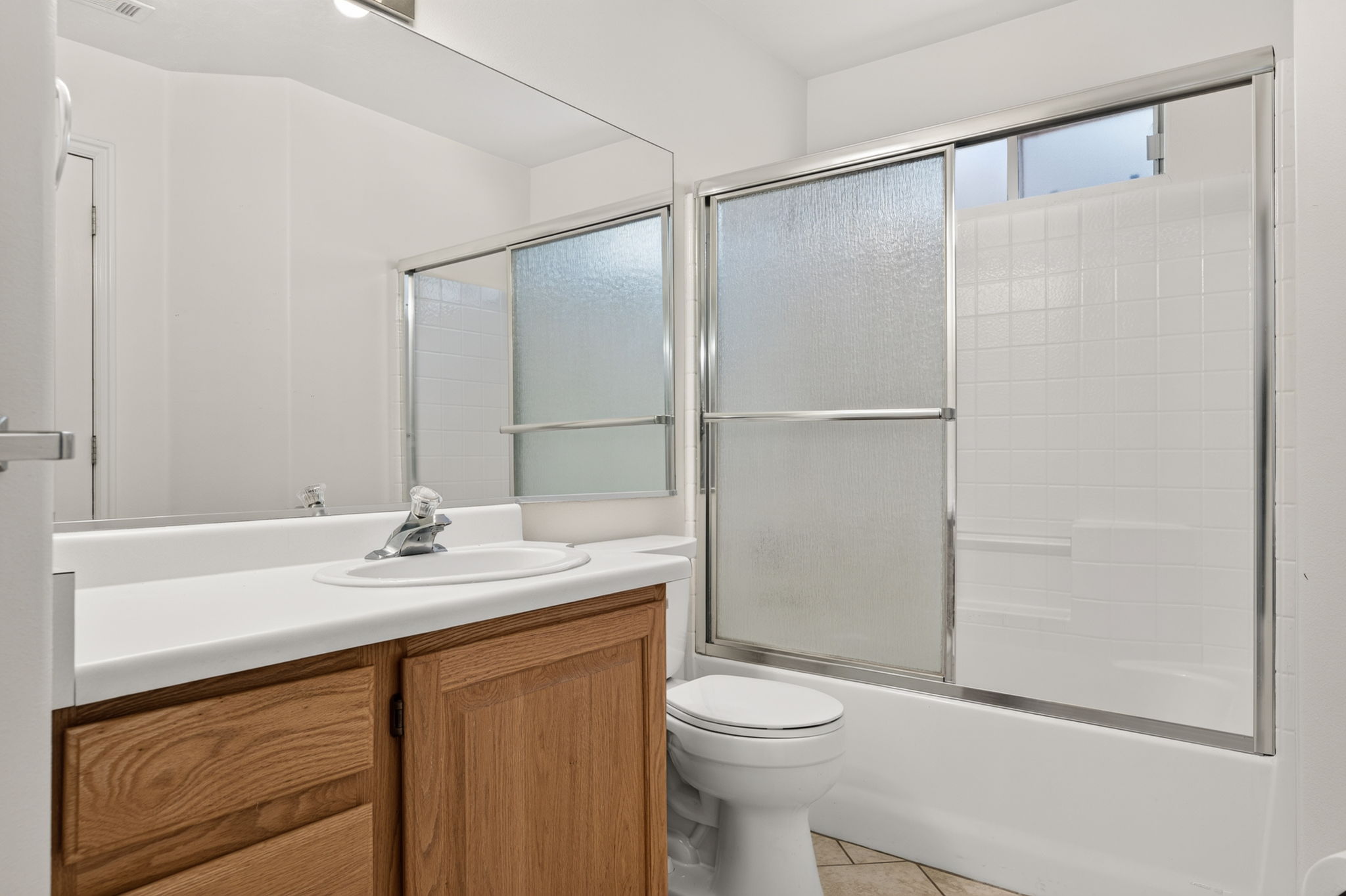 Bathroom vanity featuring a light wood-finish cabinet with a white countertop and integrated sink