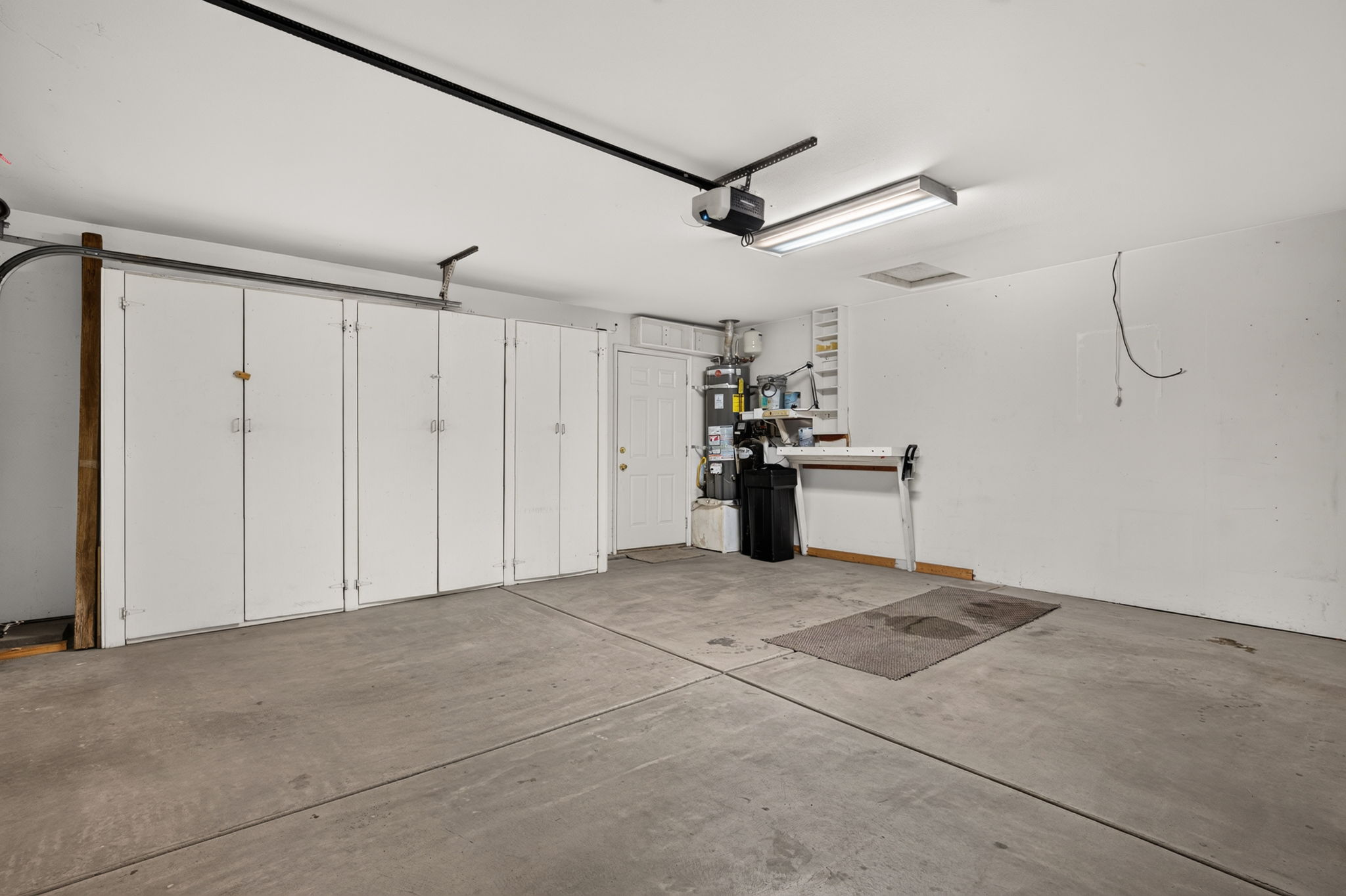 Spacious garage featuring concrete flooring and a full wall of white built-in cabinetry