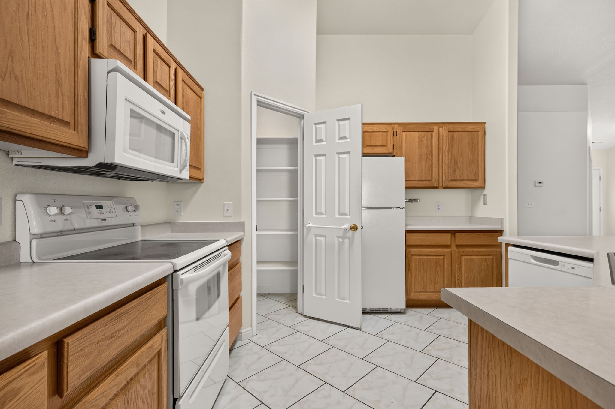 Kitchen featuring wood-finish cabinetry, light countertops, and white appliances