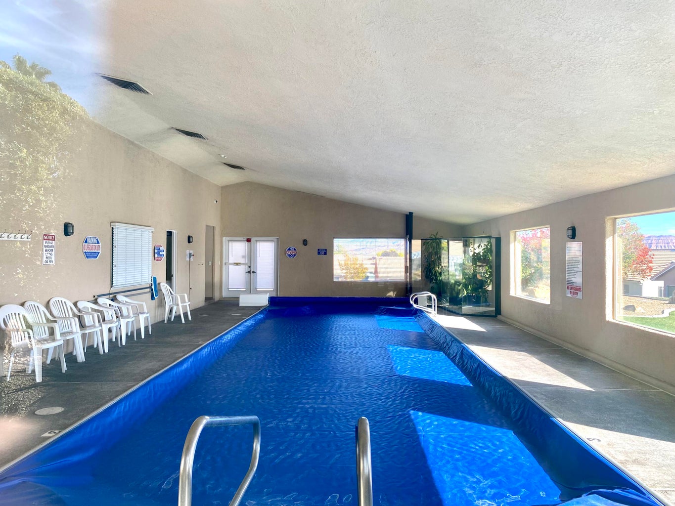 Indoor swimming pool featuring a blue pool cover, sloped ceilings, multiple windows, and recessed lighting
