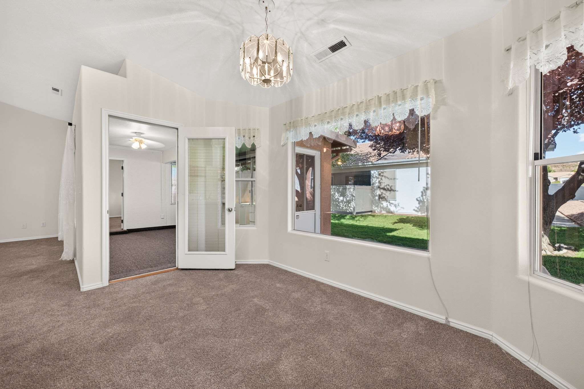 Primary Bedroom featuring a vaulted ceiling with a chandelier, two large windows, and wall-to-wall carpeting