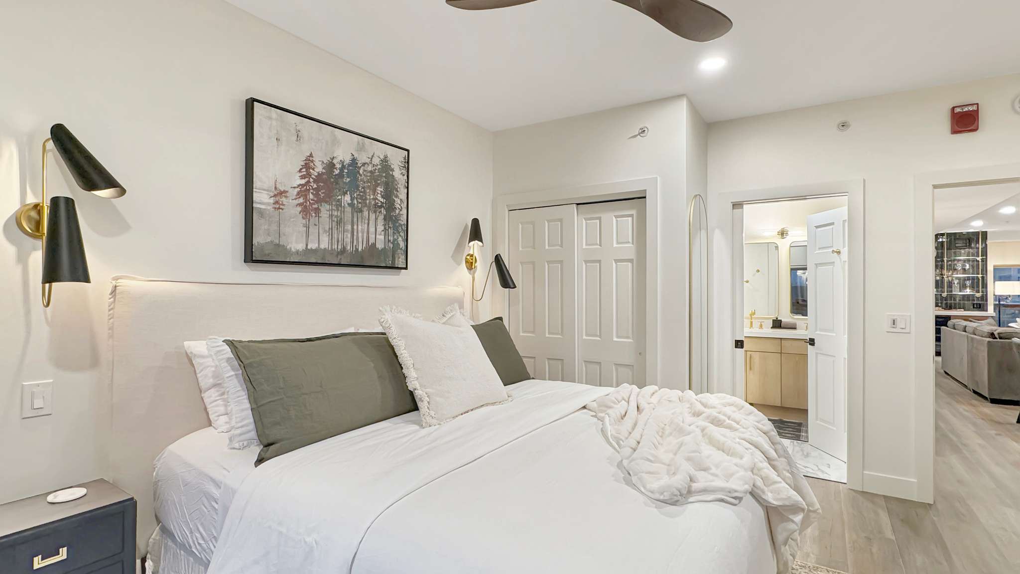 Bedroom featuring a padded headboard, dual wall-mounted sconces, bi-fold closet doors, and wood-finish flooring