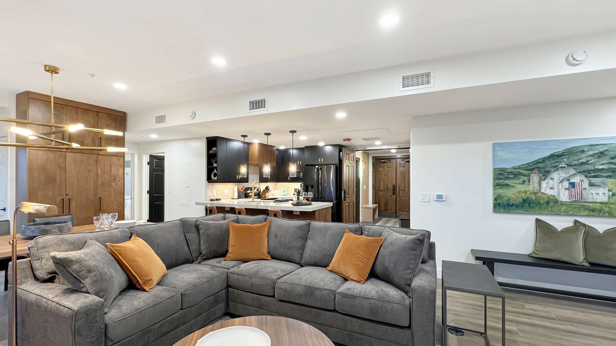 Open-concept living space featuring wood-finish flooring, recessed lighting, and a modern kitchen with dark cabinetry