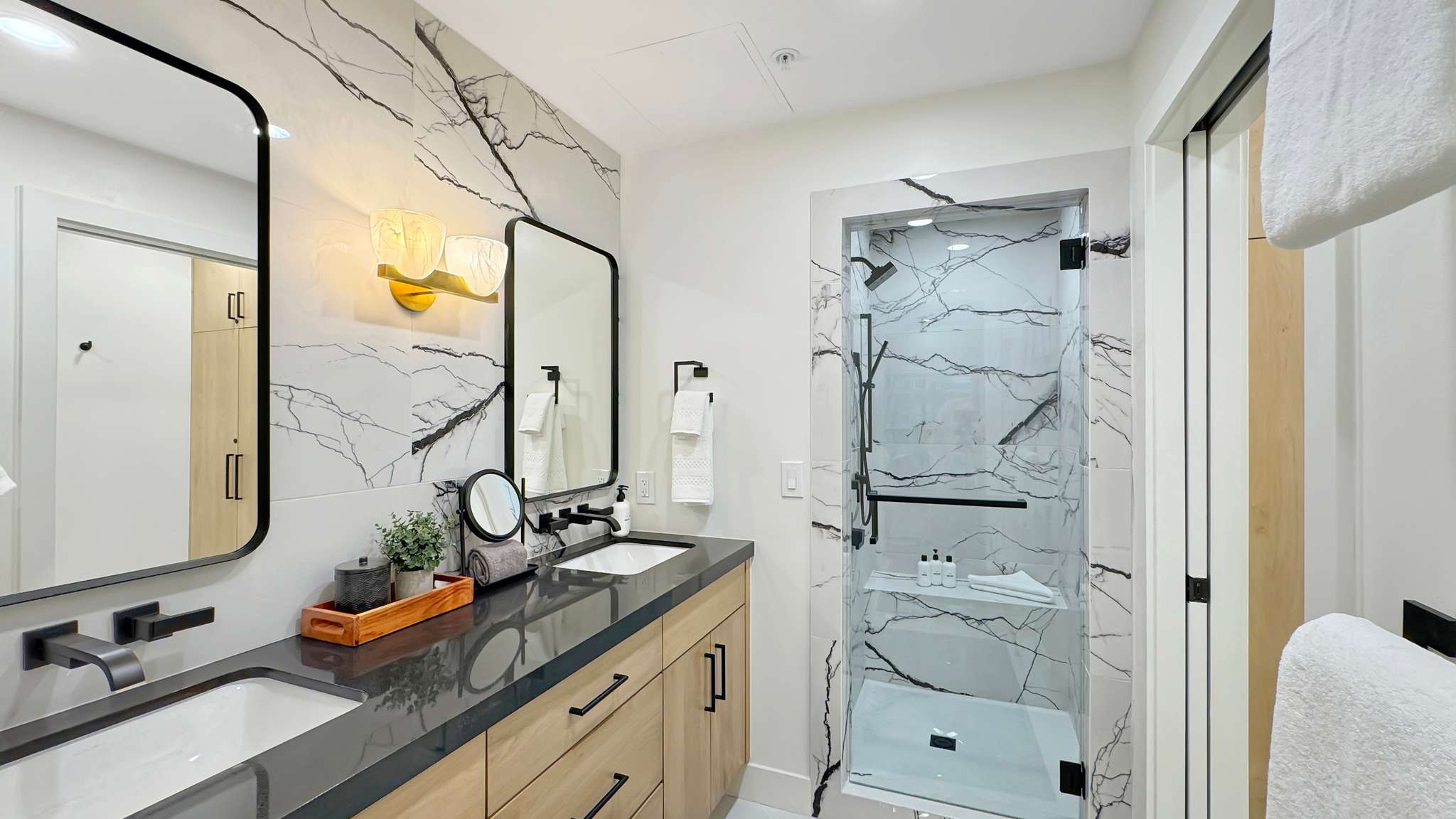 Bathroom featuring a dual-sink vanity with dark countertops and wood-finish cabinetry