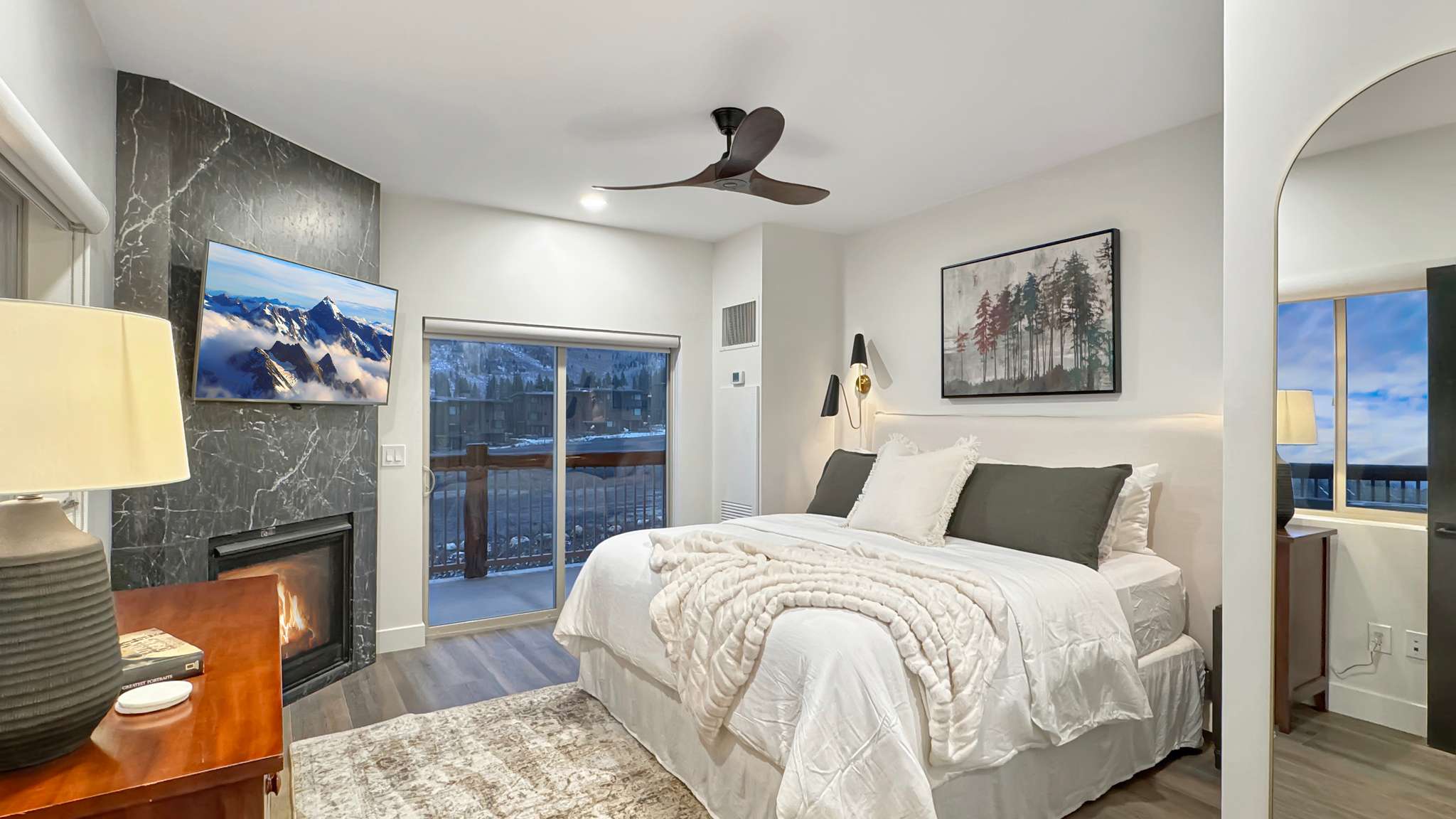 Interior space featuring wood-finish flooring, a contemporary fireplace with a stone surround, and direct access to an outdoor balcony through sliding glass doors