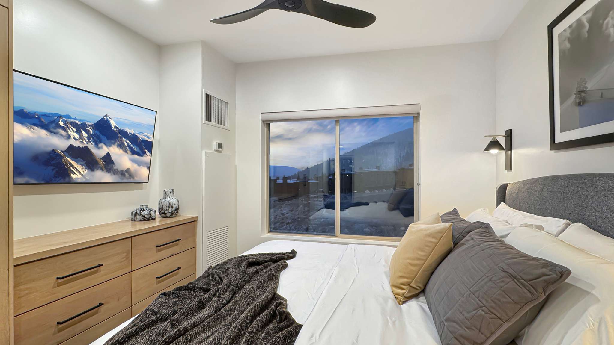 Bedroom featuring a large window, a ceiling fan, and built-in dresser cabinetry with dark hardware