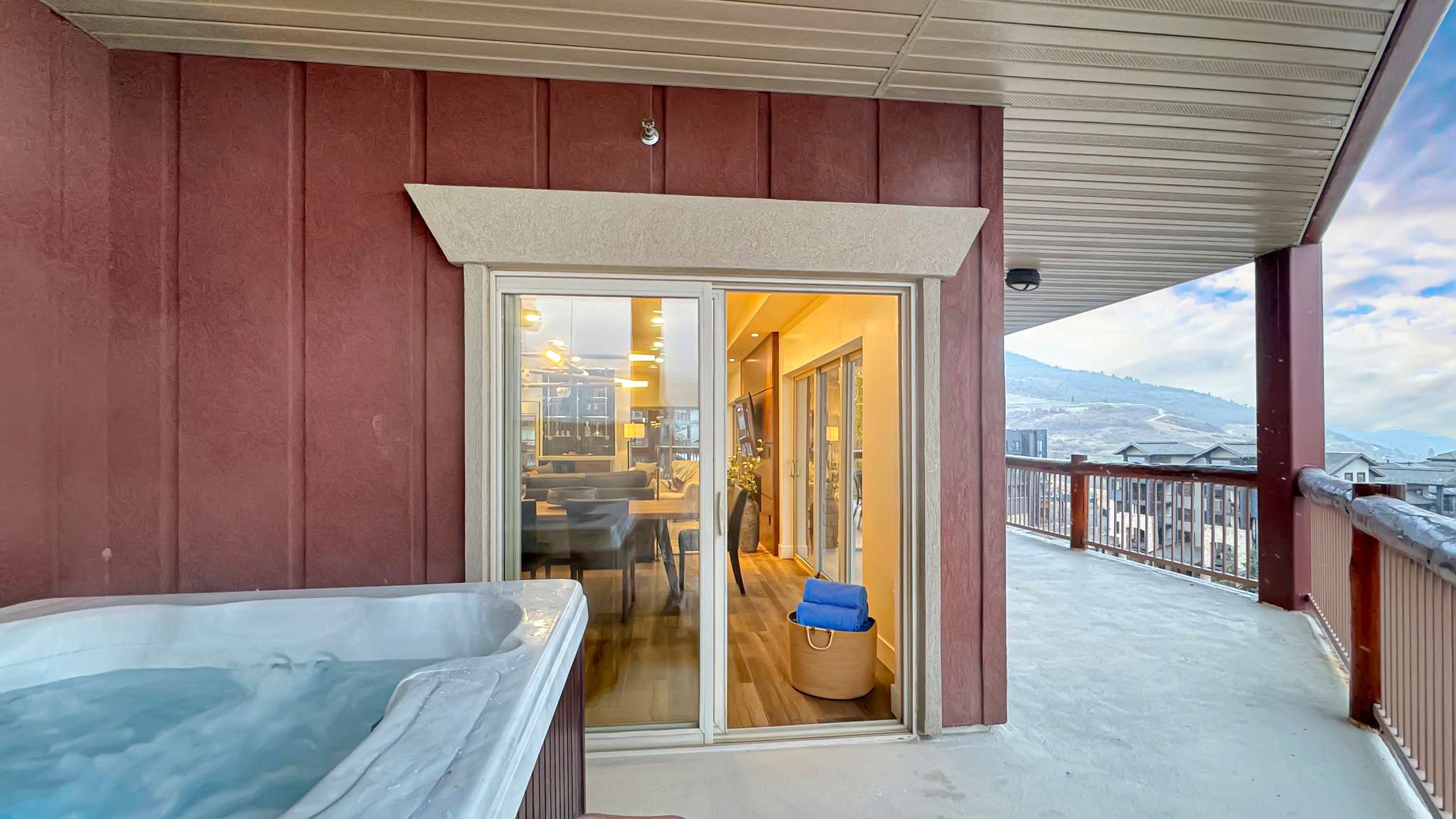 Outdoor hot tub with mountain background, expansive deck, and sliding glass door access to the interior