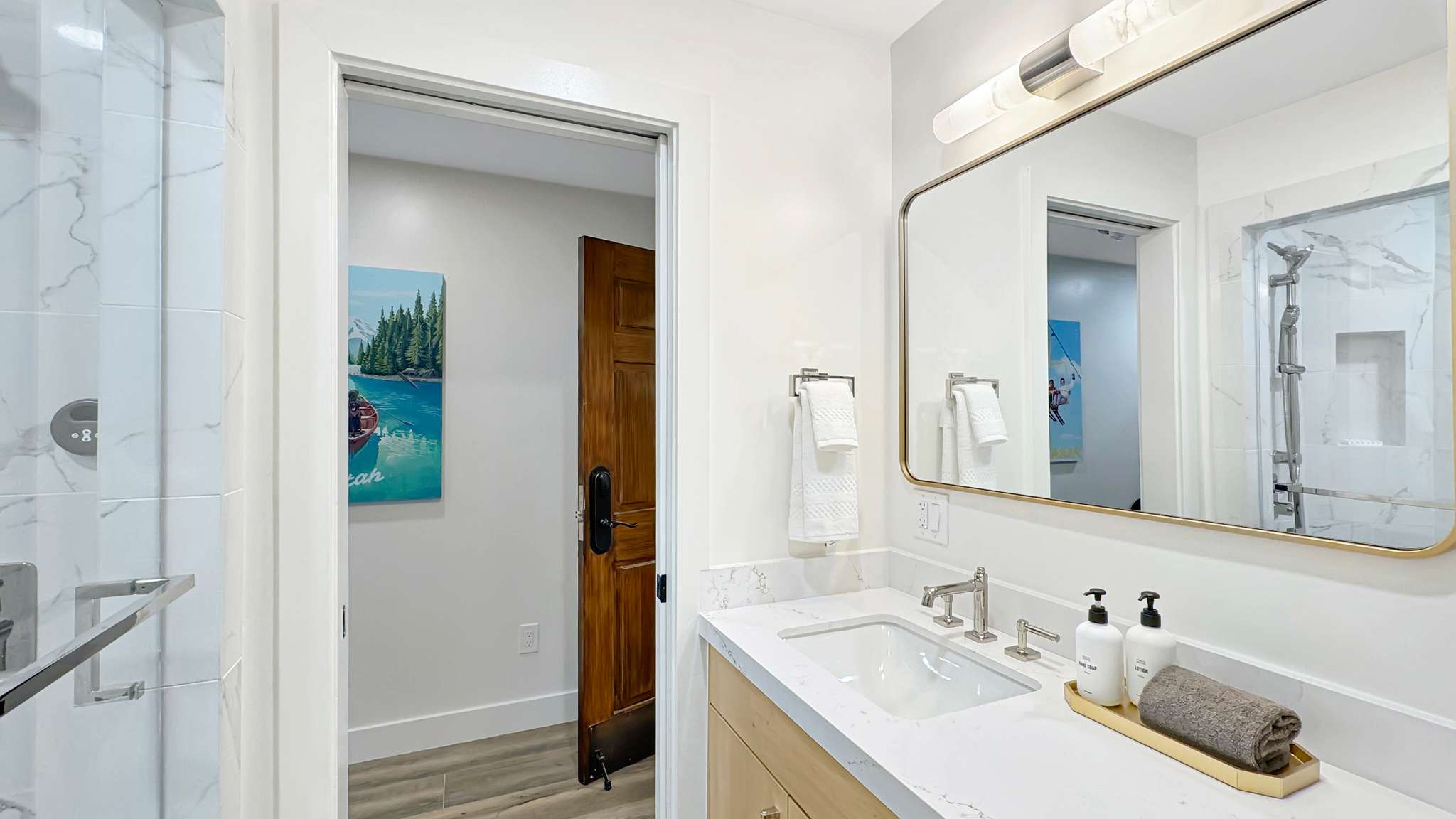 Contemporary bathroom featuring a vanity with a white countertop and undermount sink, a large framed mirror, and a wall-mounted light fixture