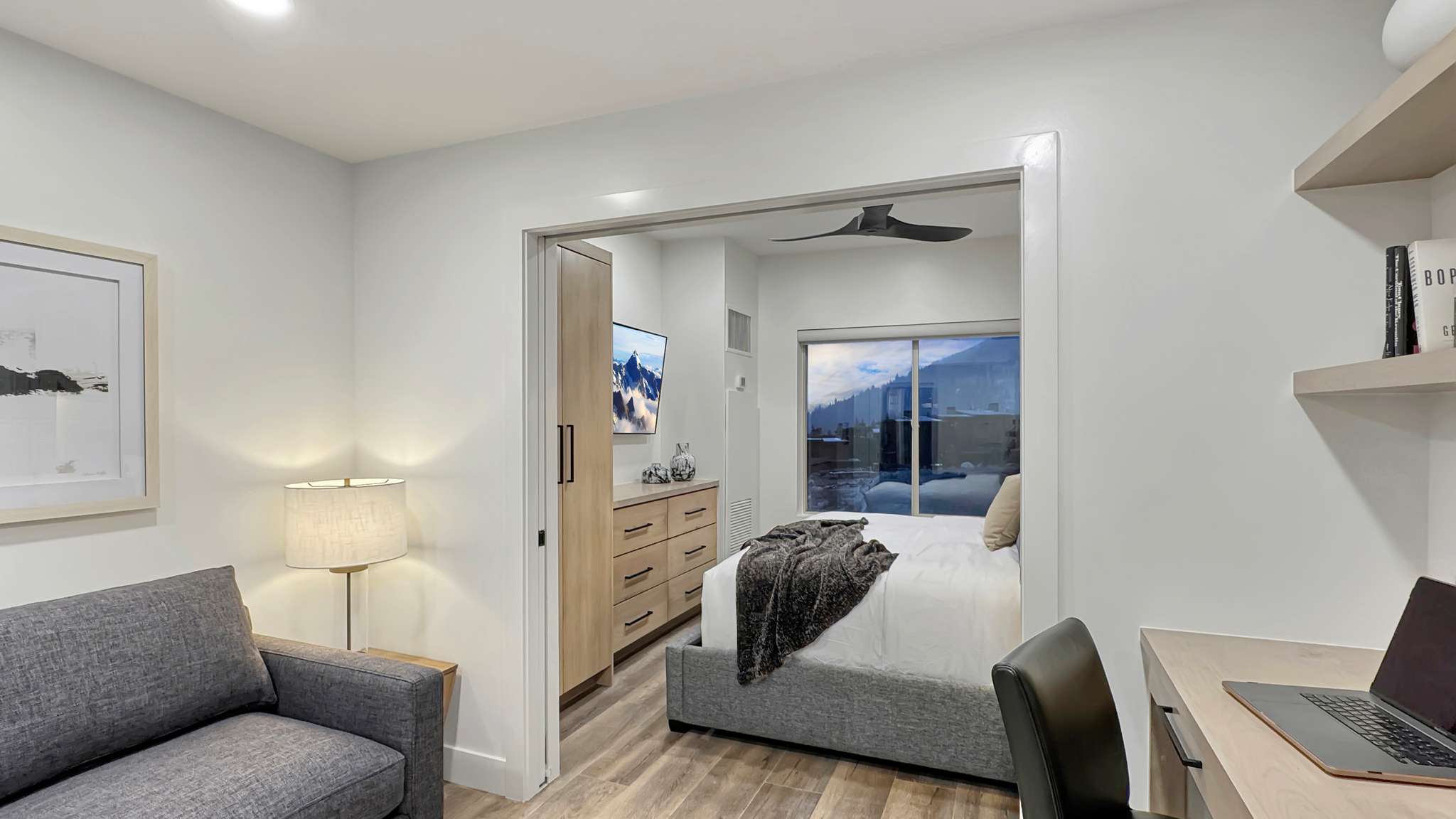 Open concept bedroom area featuring wood-finish flooring and a bright window with mountain scenery