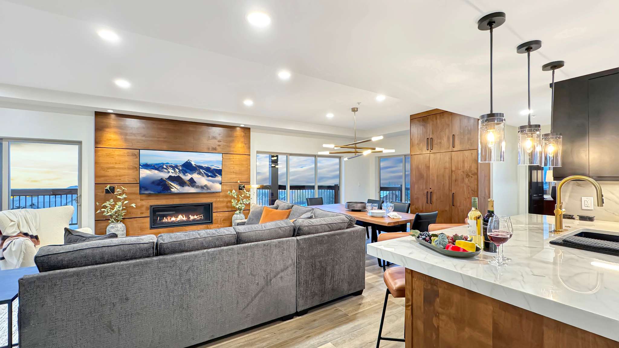 Open-concept living space featuring a wood-panelled accent wall with an inset fireplace and television