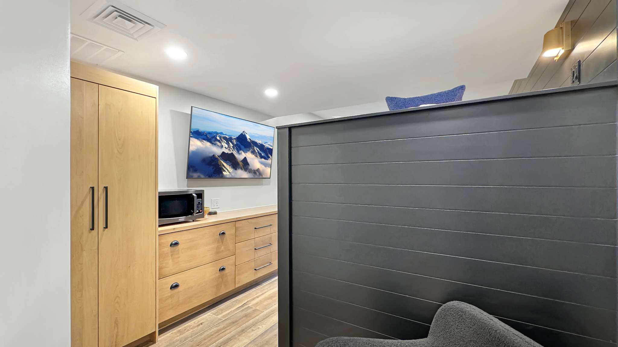 Built-in blonde wood cabinetry with matte black hardware, integrated storage, and recessed lighting