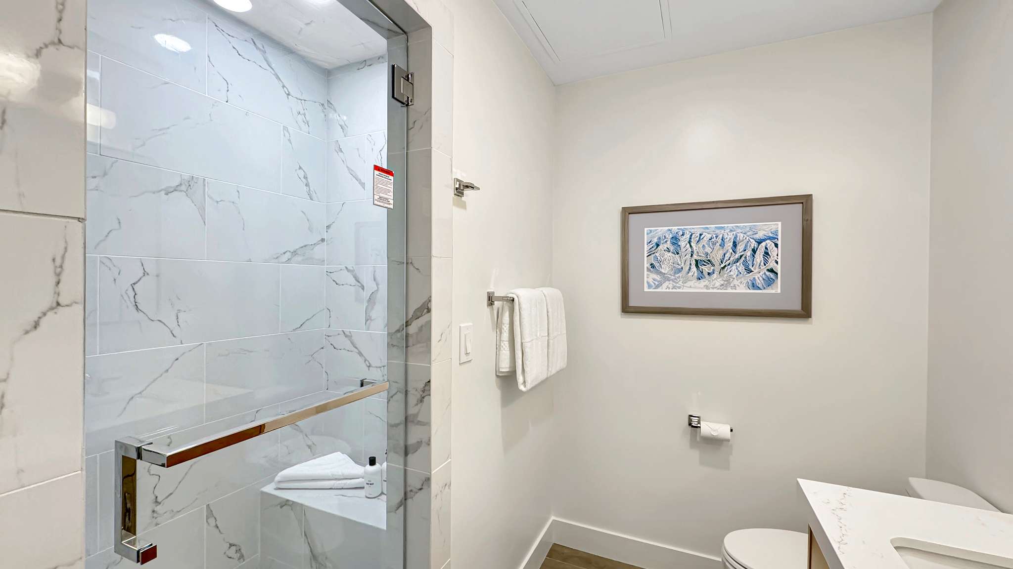 Shower enclosure with clear glass door, chrome hardware, and white marble-look tile