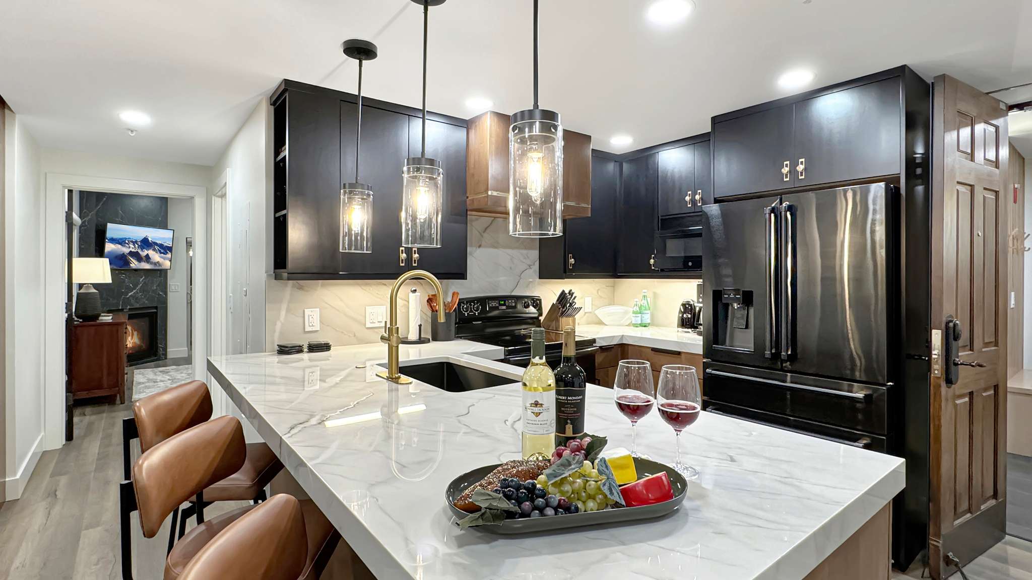 Contemporary kitchen featuring a large island with a waterfall countertop, integrated sink with a gold-tone faucet, and pendant lighting