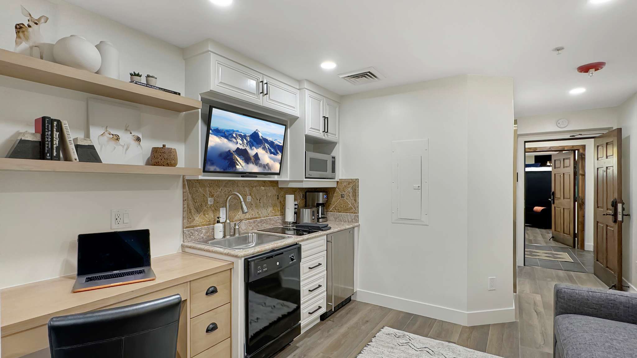 Compact kitchen with white shaker cabinetry, stainless steel sink, and light-toned countertop