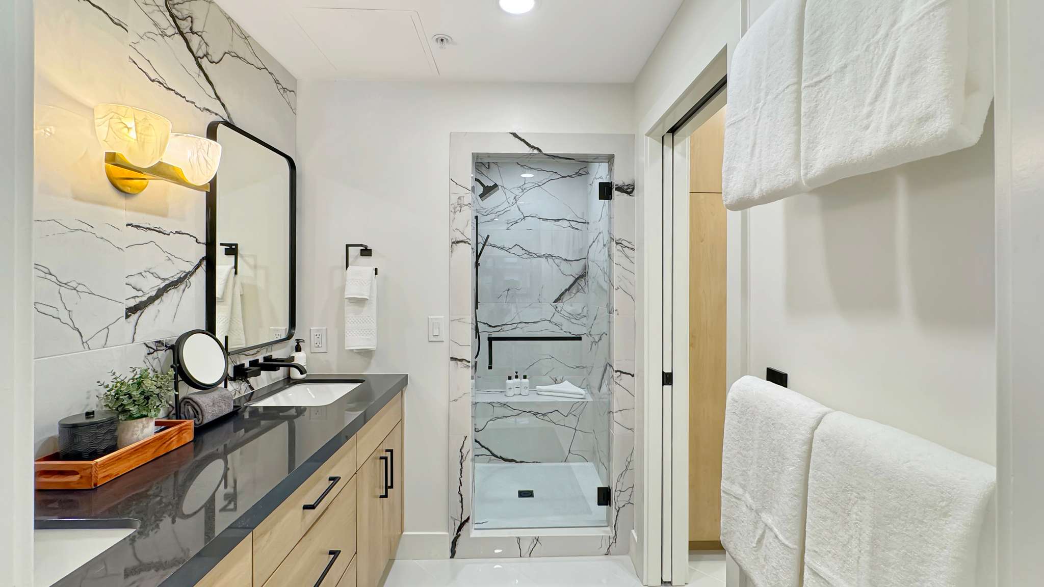Bathroom featuring a dual vanity with wood-finish cabinetry, dark countertop, and integrated sinks