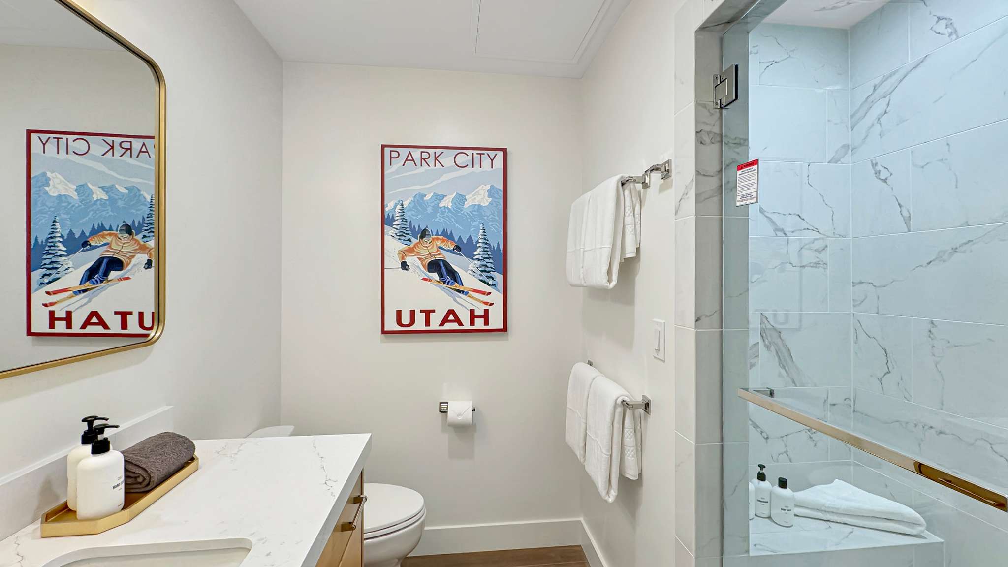 Bathroom featuring a walk-in shower with glass enclosure, white marbled tile, a built-in shower bench, and a gold-toned shower handle