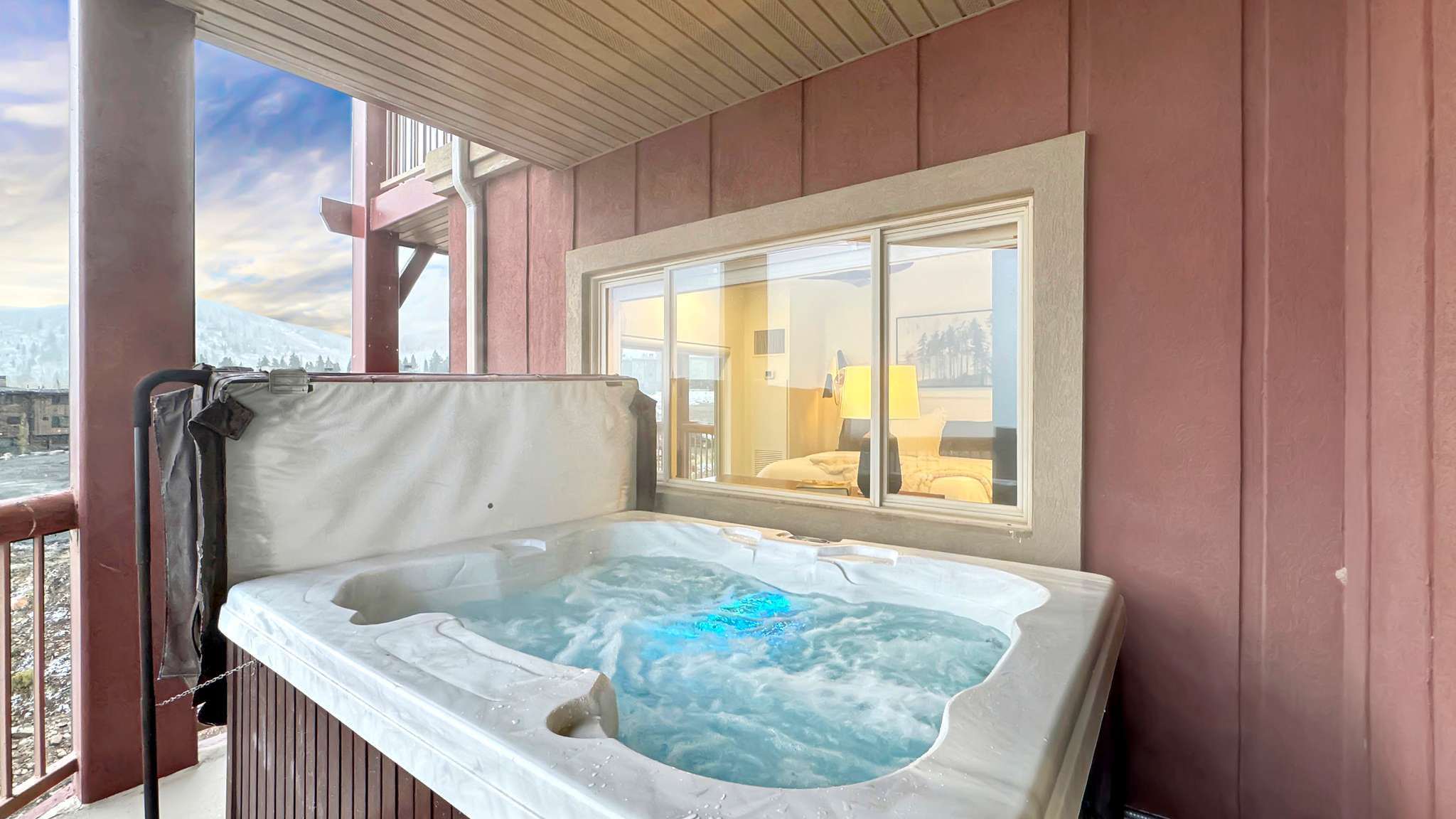 Private outdoor hot tub with integrated lighting, wood-paneled base, and mountain scenery