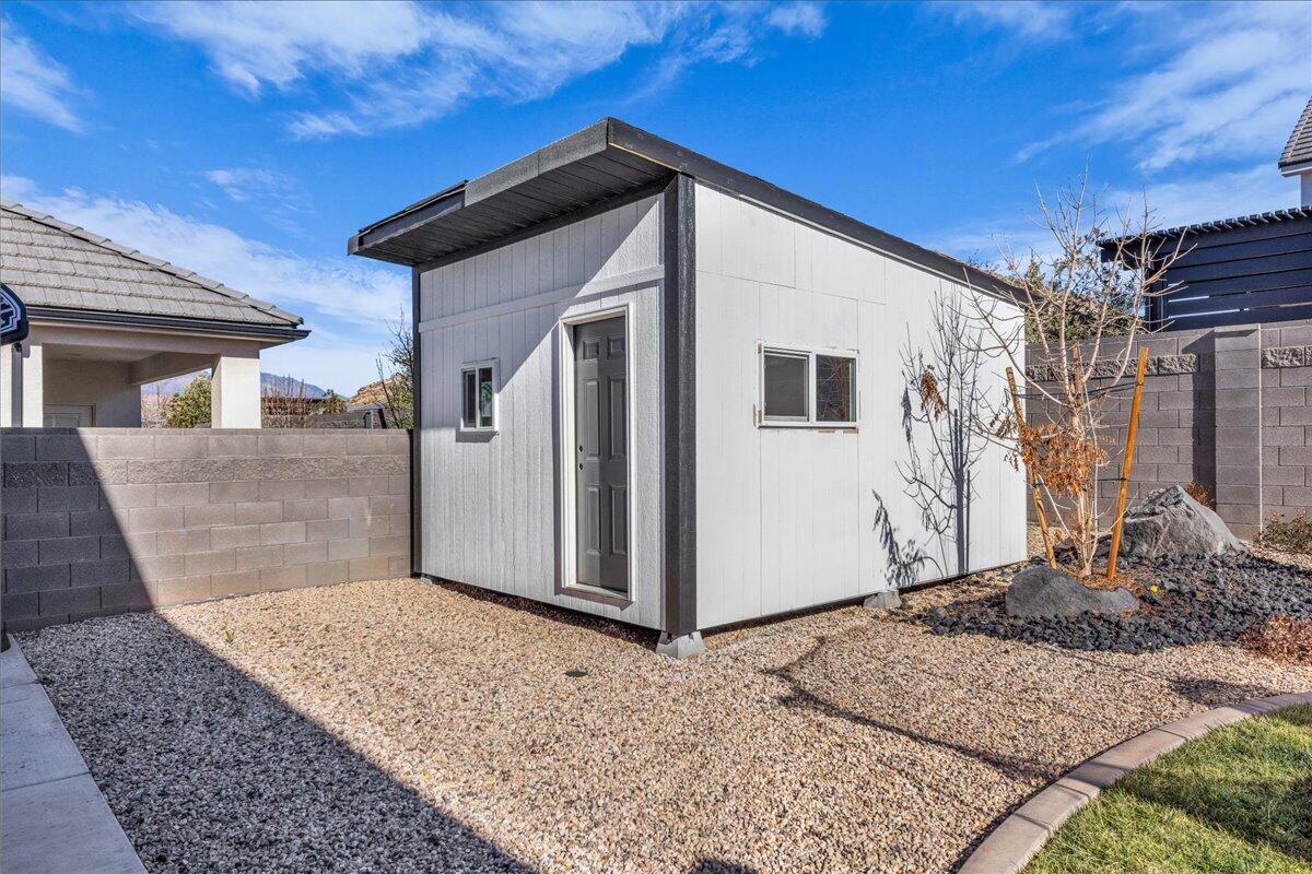 Detached exterior structure featuring white vertical siding, a flat roofline, and a gray entry door