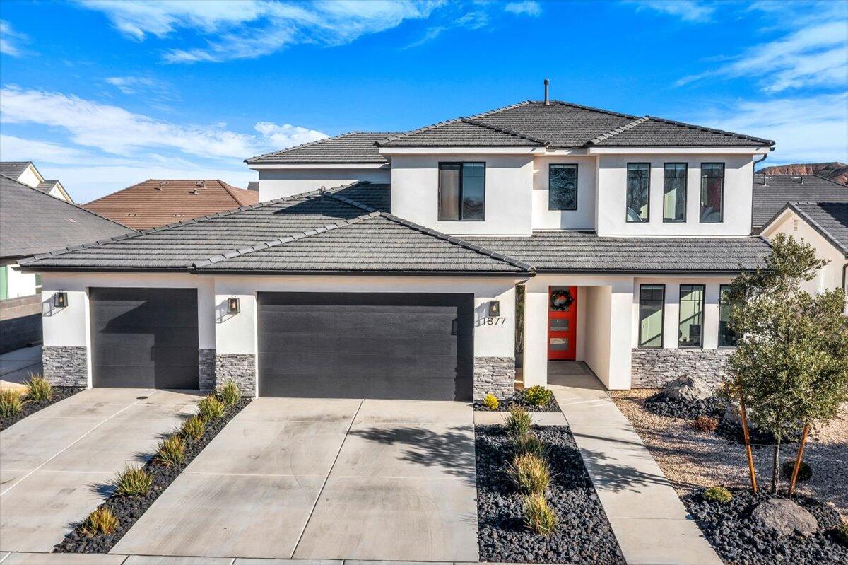 Modern two-story residence featuring a tile roof and a stucco exterior with stone accents