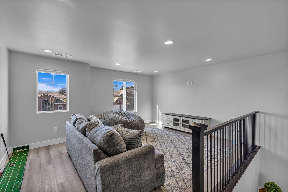 Spacious upper-level room featuring light gray walls, recessed lighting, and wood-finish flooring