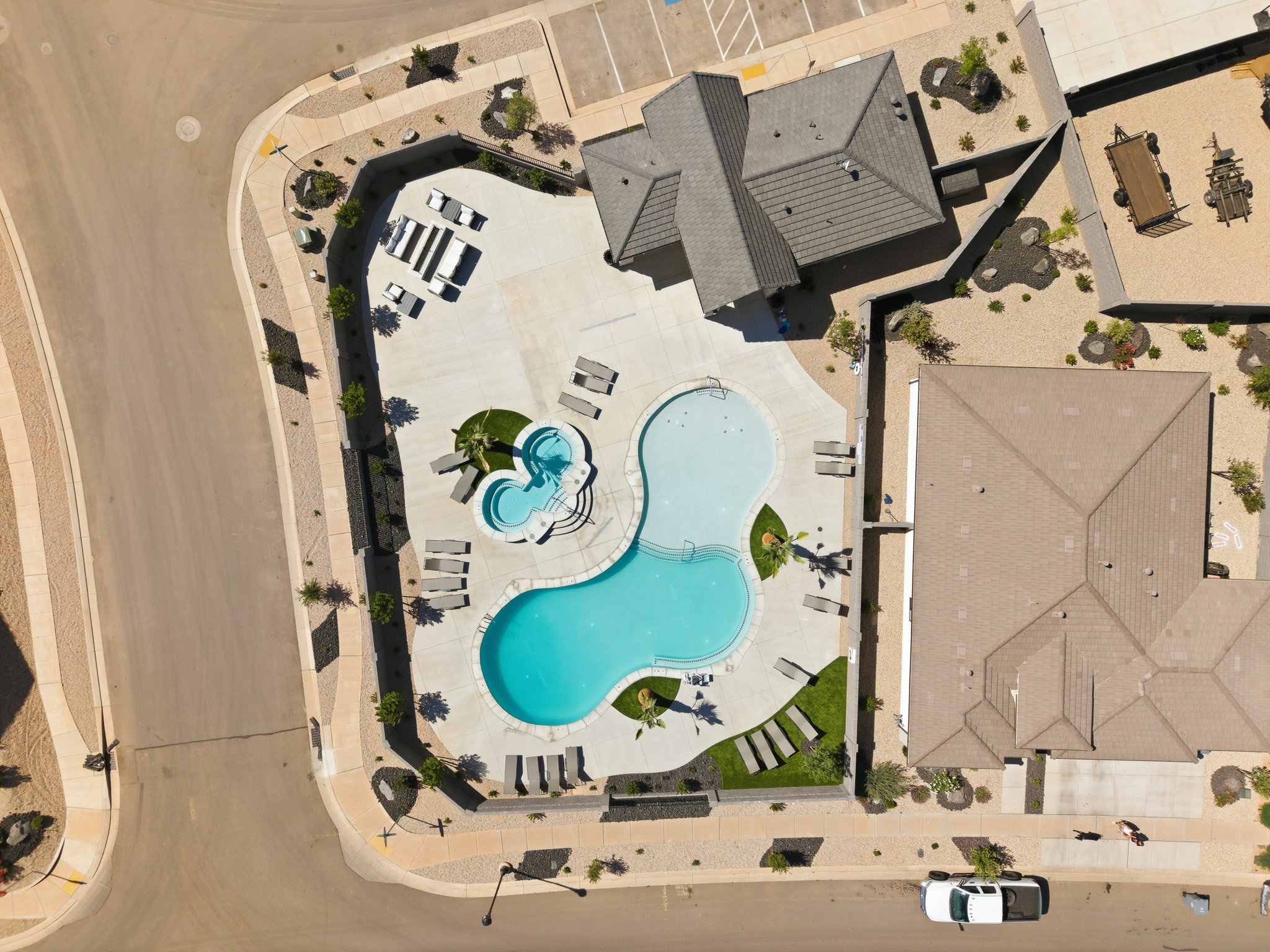 Community swimming pool with an integrated spa, surrounded by a concrete deck and multiple lounge chairs