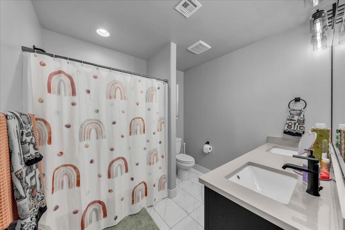 Bathroom featuring a dual vanity with light-toned countertops, contemporary black faucets, and under-mount sinks