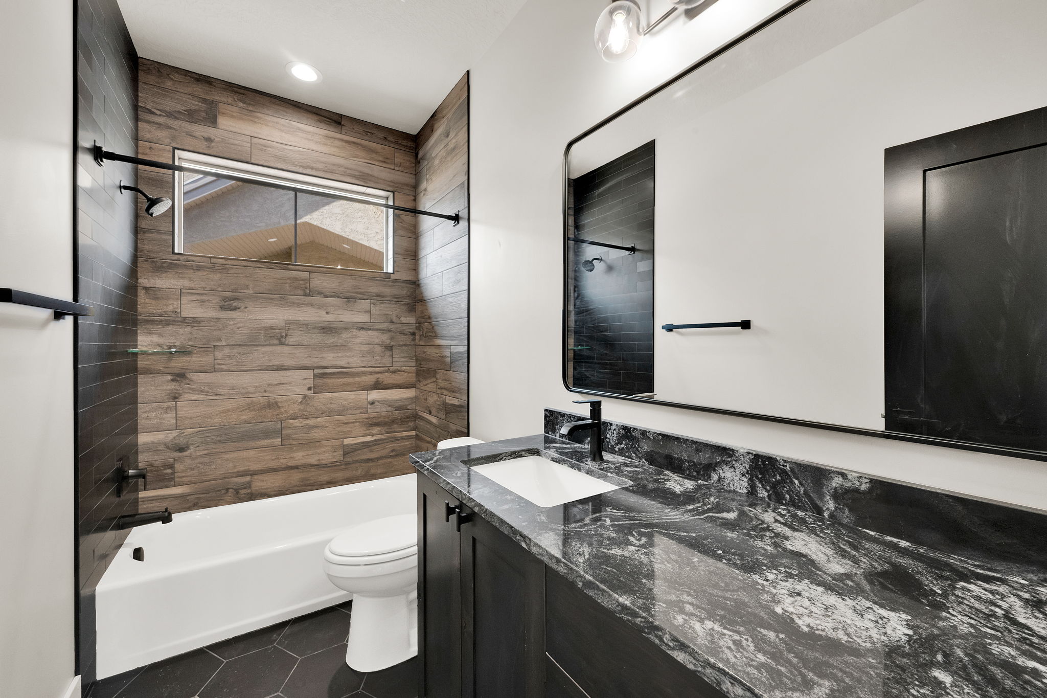 Bathroom featuring a tub/shower combination with wood-finish tile surround and horizontal window