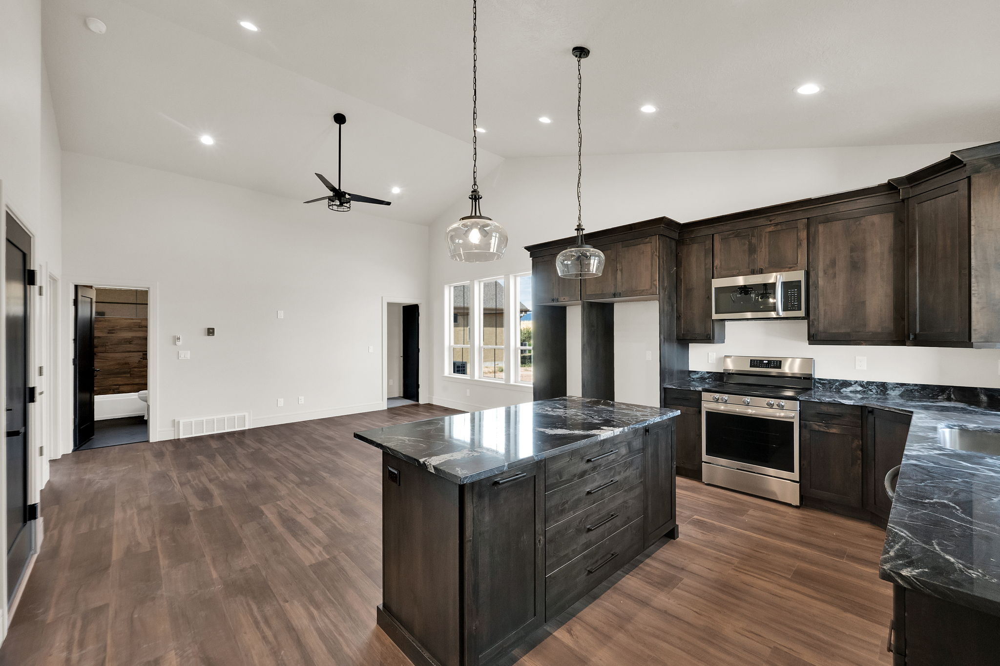 Modern kitchen featuring dark wood cabinetry, stainless steel appliances, and a central island with a contrasting stone countertop