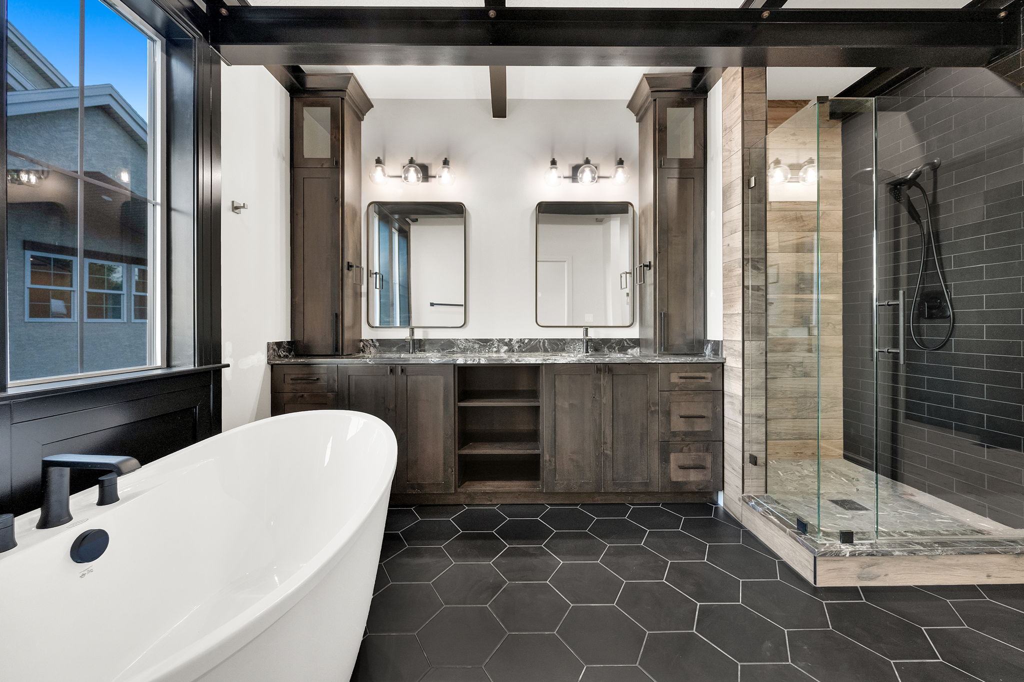 Spacious bathroom featuring a freestanding tub, hexagonal floor tiling, and a glass-enclosed shower with subway tile surround