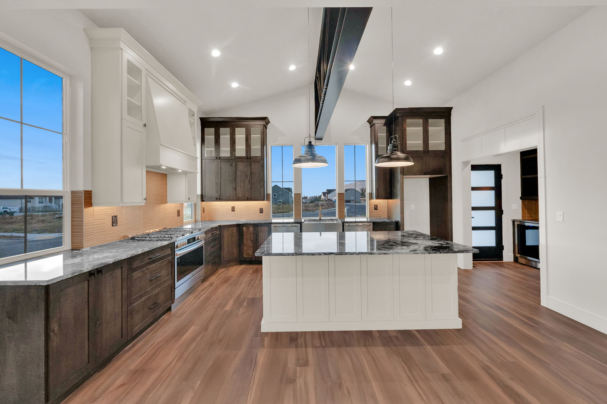 Open-concept kitchen featuring wood-finish flooring, a two-toned cabinetry scheme, and an island with a white beadboard base