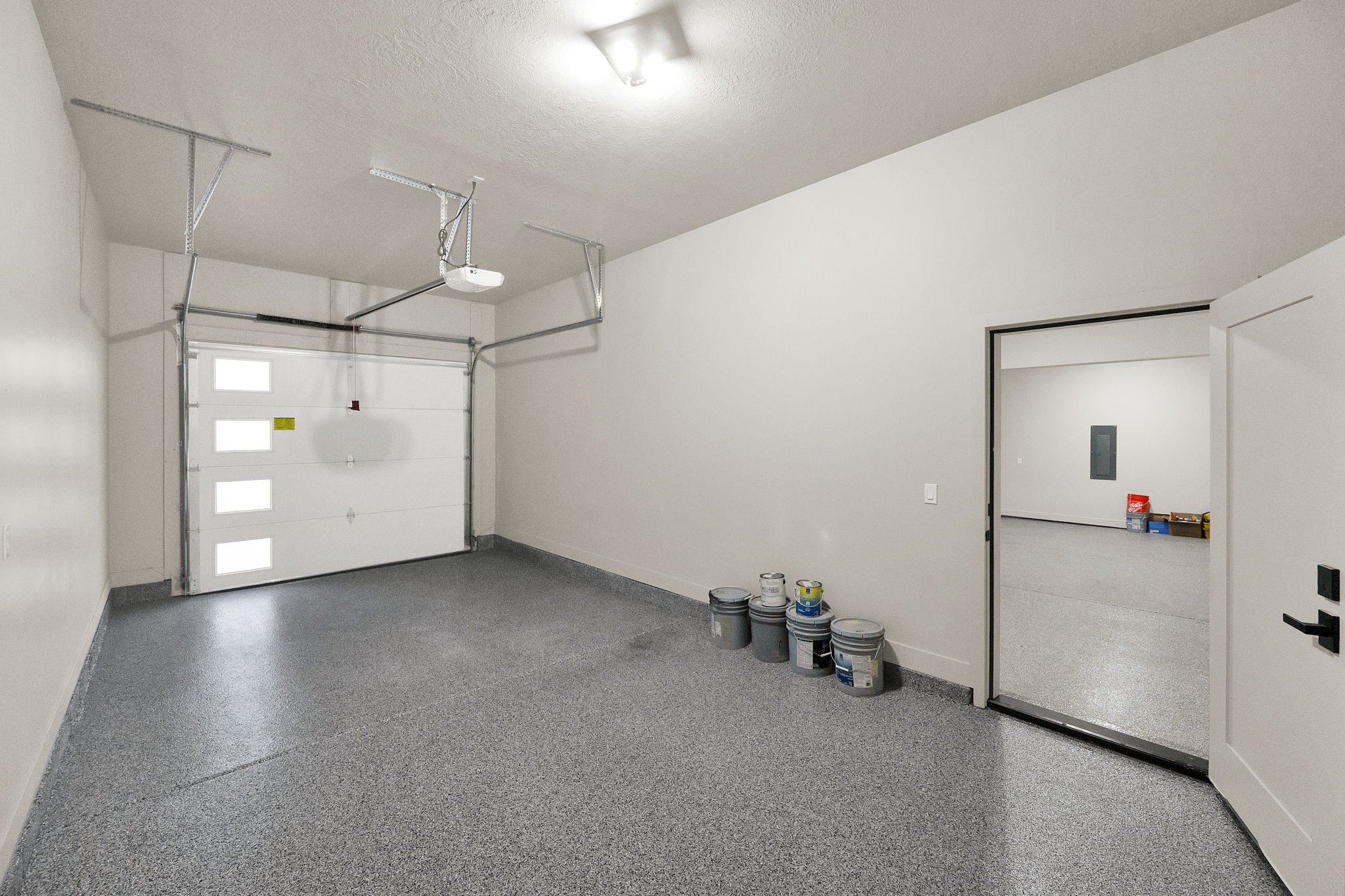 Spacious garage featuring a modern sectional garage door with frosted window panels, an automatic garage door opener, and durable speckled epoxy flooring
