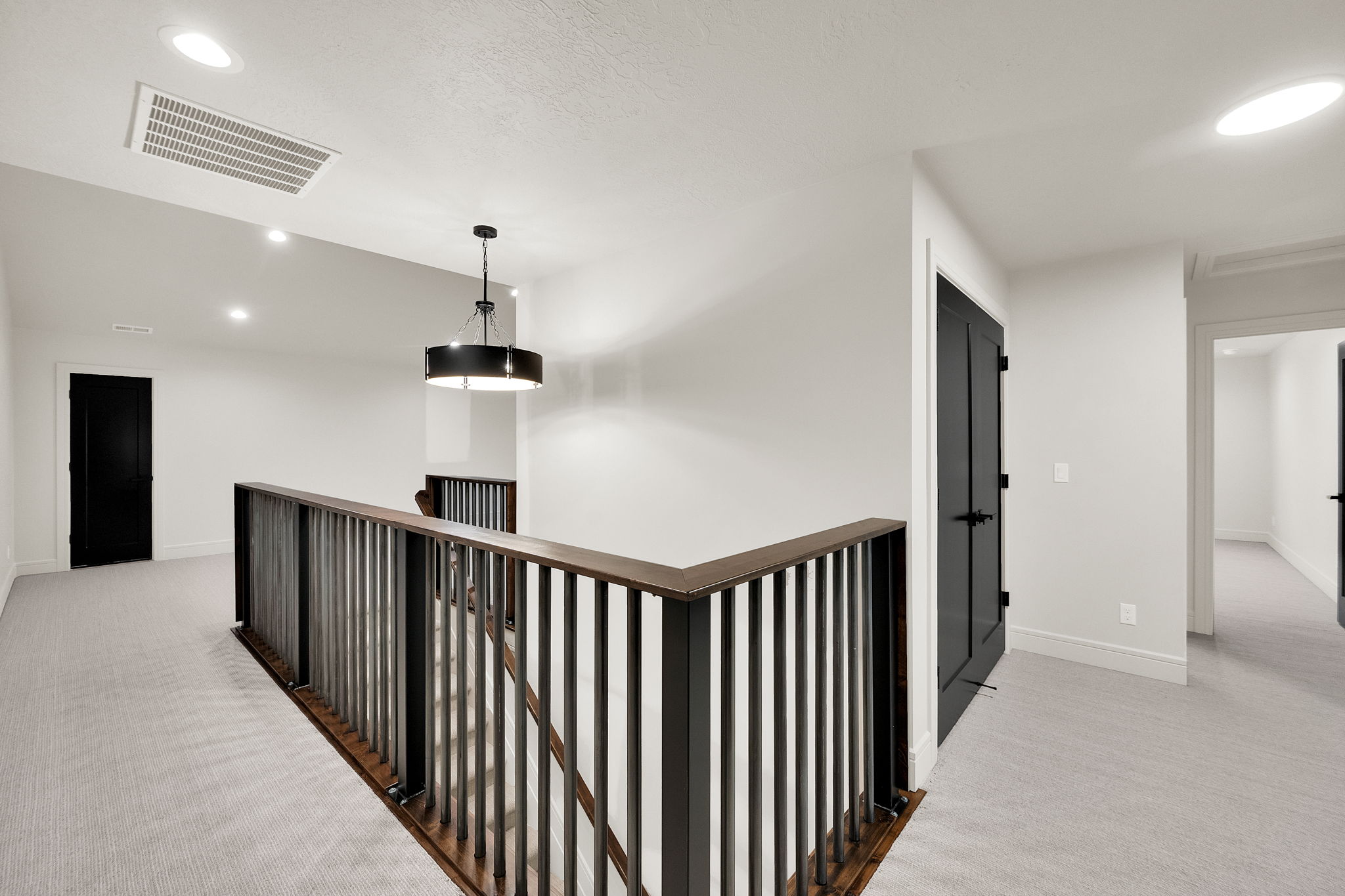 Upper-level landing featuring light-toned carpeting, white walls, and dark-toned doors