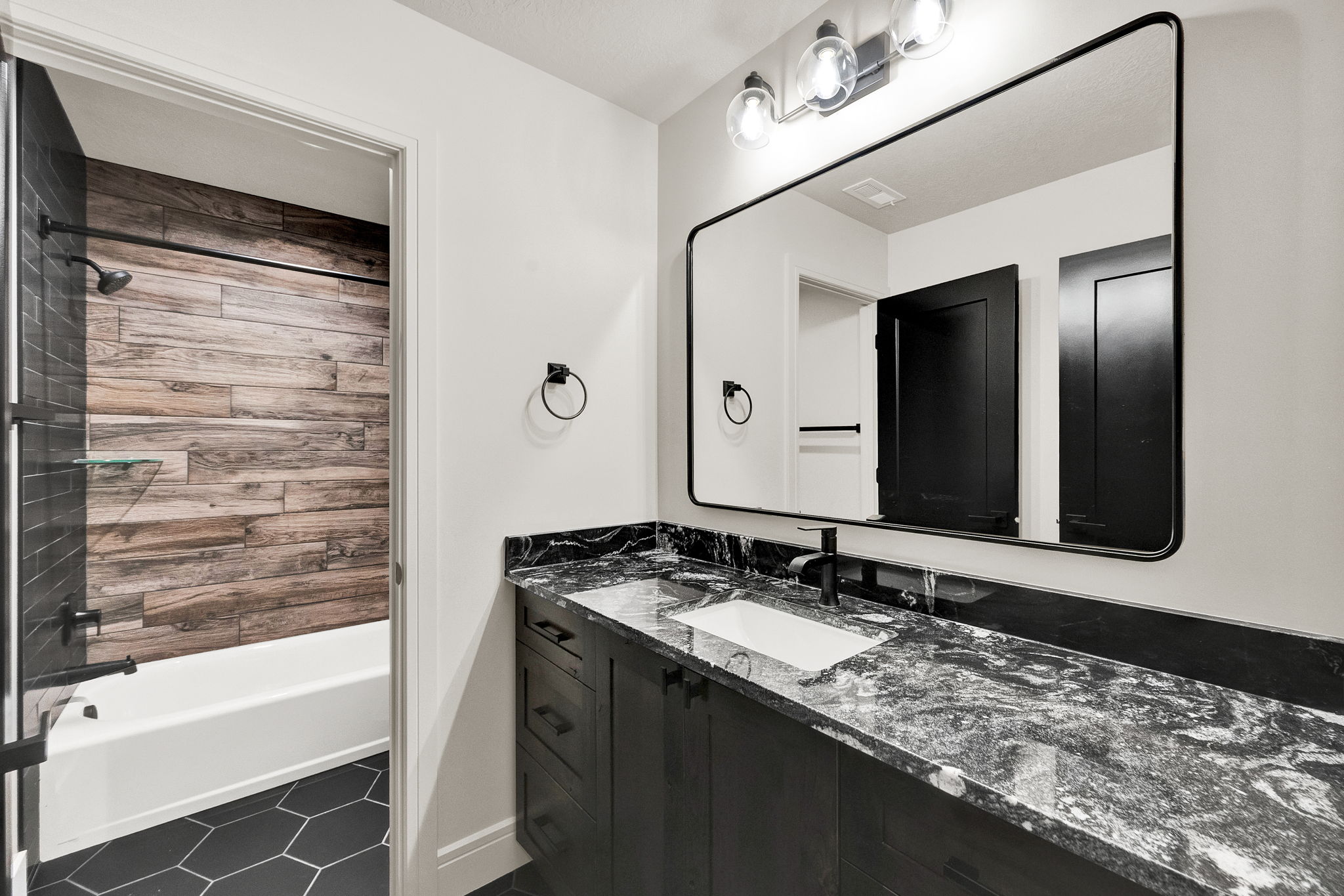 Bathroom vanity featuring a dark stone countertop with integrated sink and modern black faucet