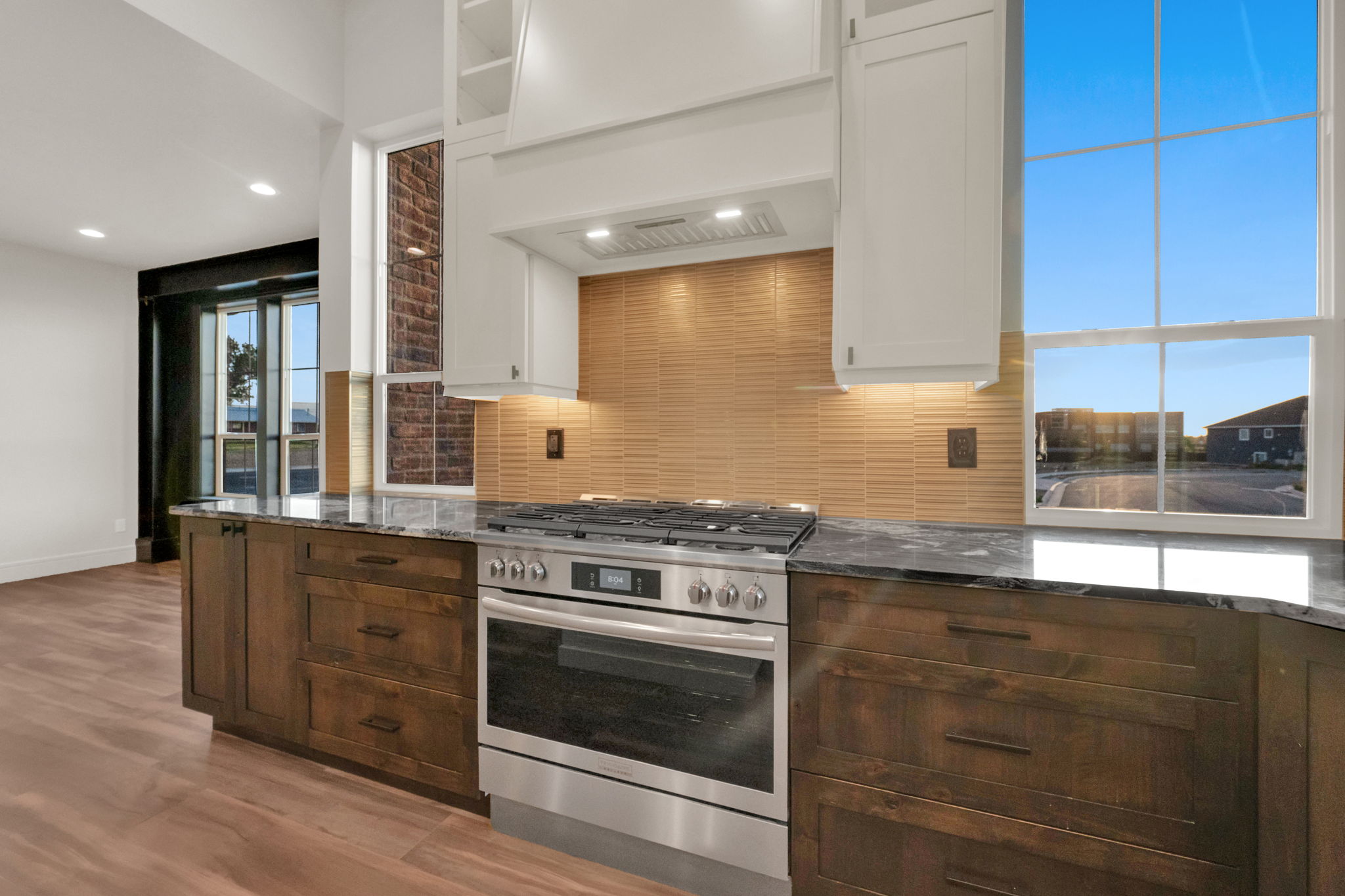 Modern kitchen featuring a stainless steel range, rich wood-finish base cabinetry, and light-toned upper cabinetry