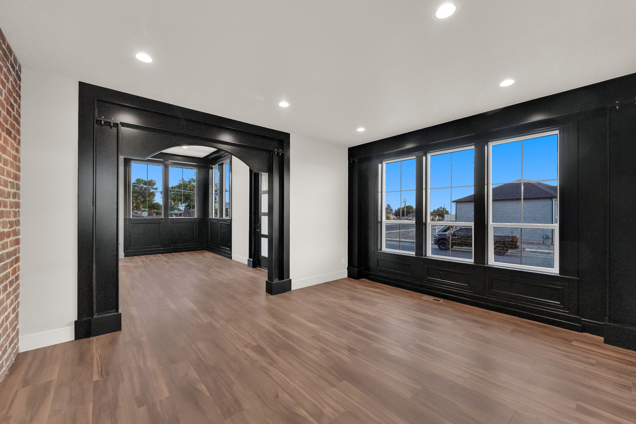 Spacious interior featuring wood-finish flooring, a prominent black arched entryway, and recessed lighting