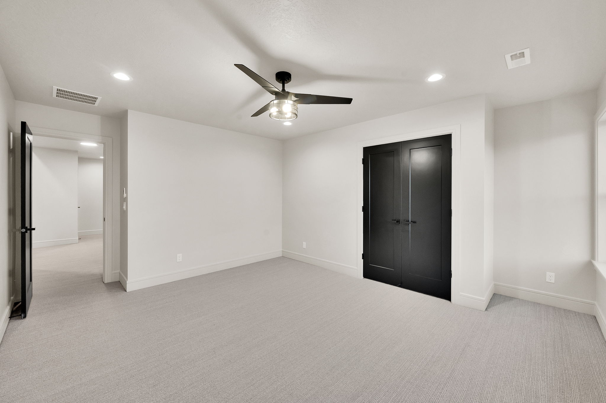 Spacious room featuring light-colored carpeting, recessed lighting, and a modern ceiling fan