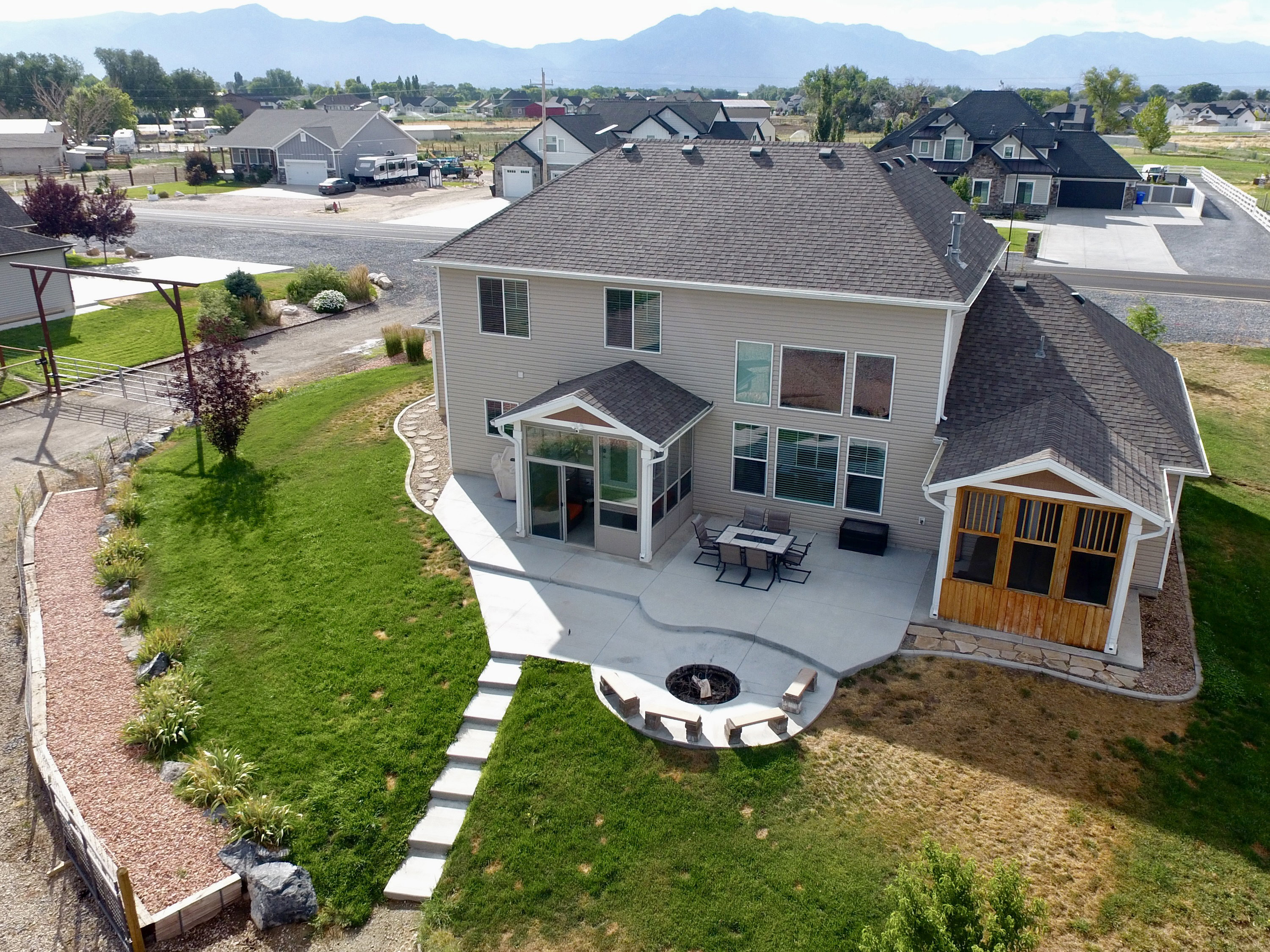 Spacious backyard featuring an extensive concrete patio, built-in fire pit with bench seating, and a covered screen porch