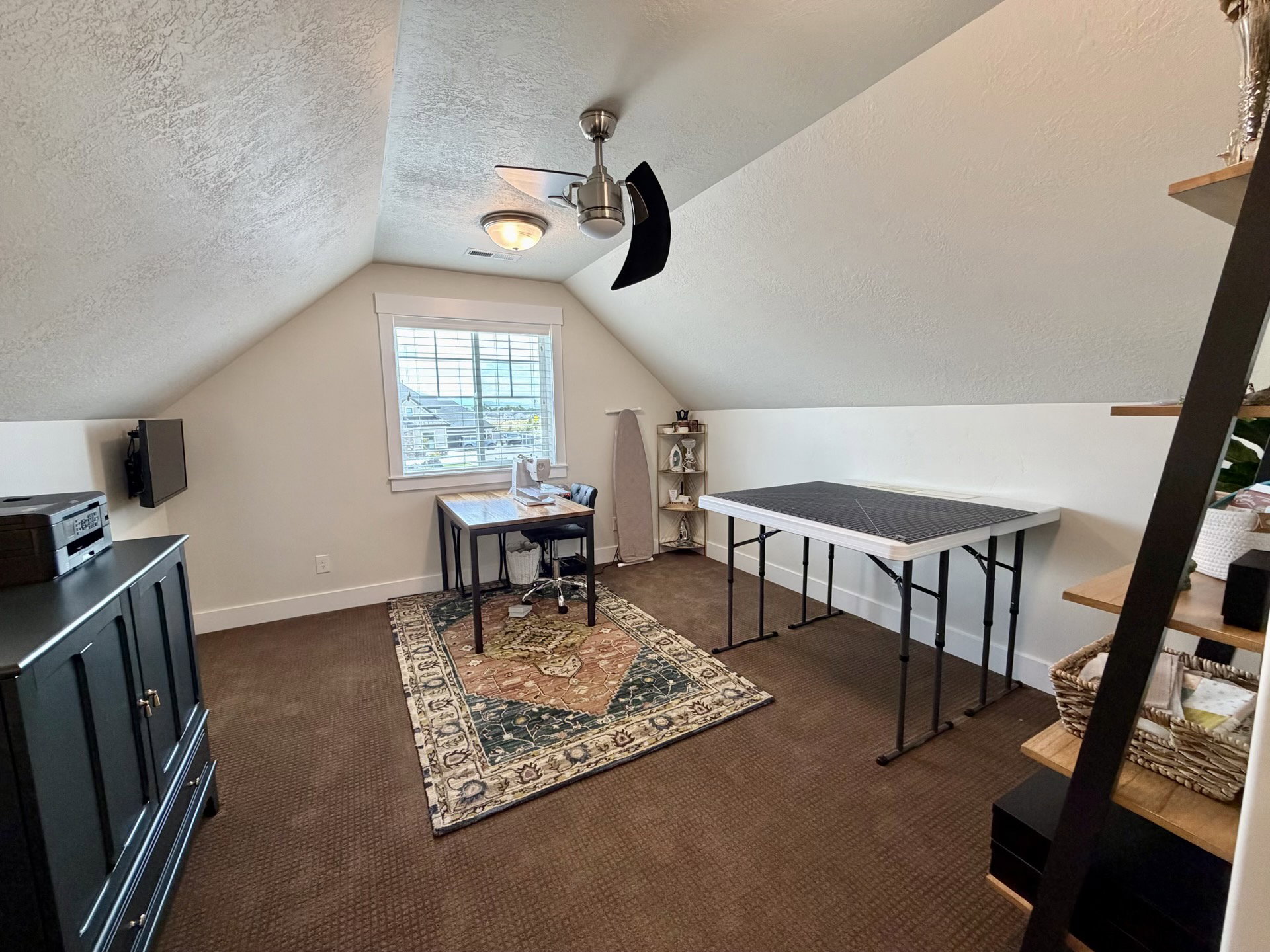 Attic room featuring sloped ceilings, a window with horizontal blinds, and textured wall finishes
