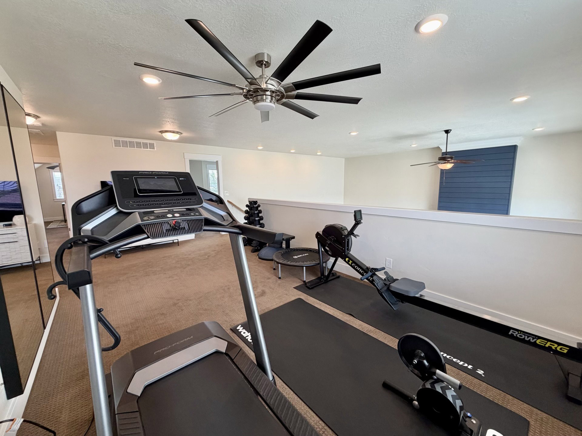 Open loft area featuring recessed lighting, ceiling fans, a partial wall, and a blue accent wall