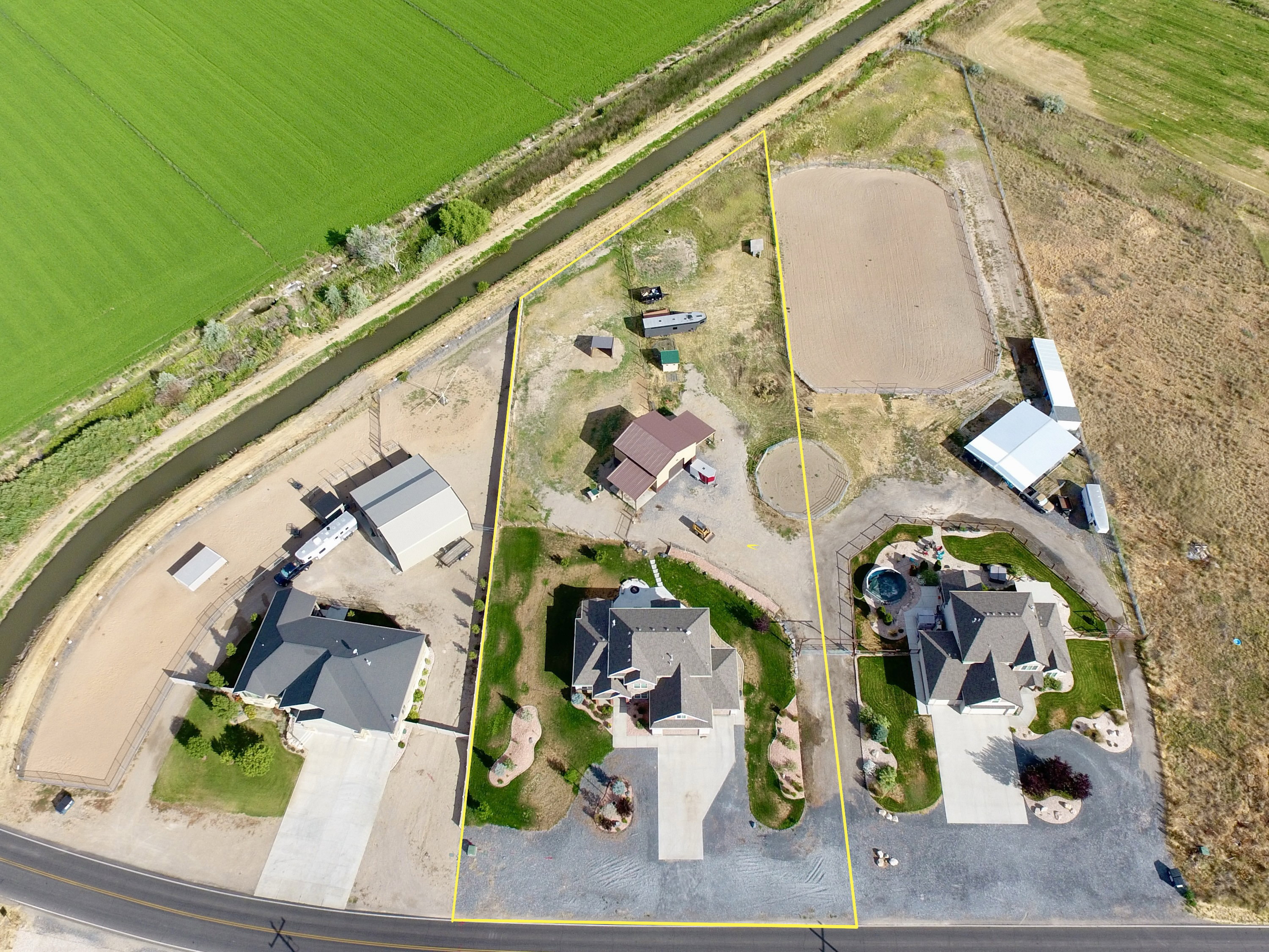 Expansive property featuring a paved driveway, detached garage, and a large arena