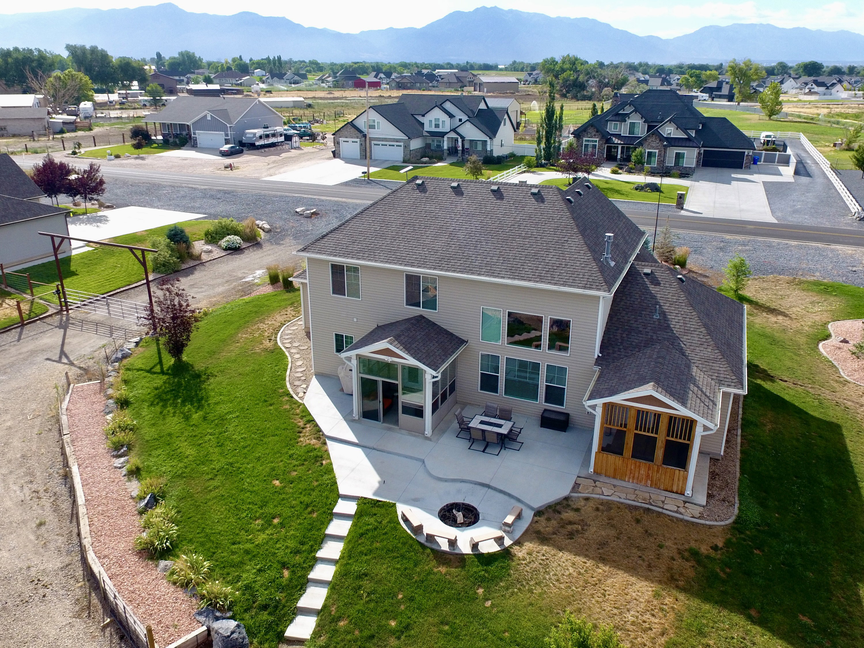 Rear exterior showcasing a spacious concrete patio with a built-in fire pit