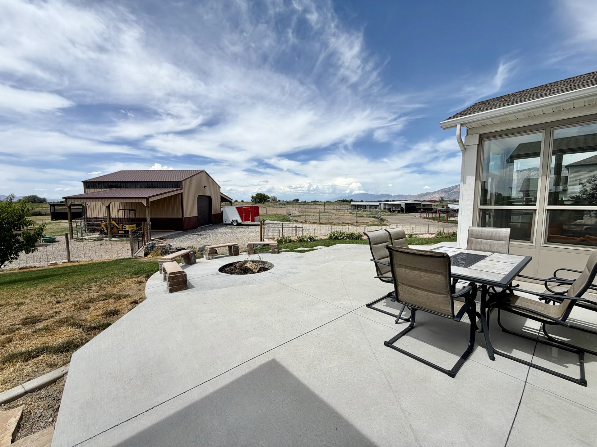 Expansive concrete patio featuring a built-in fire pit with stone seating