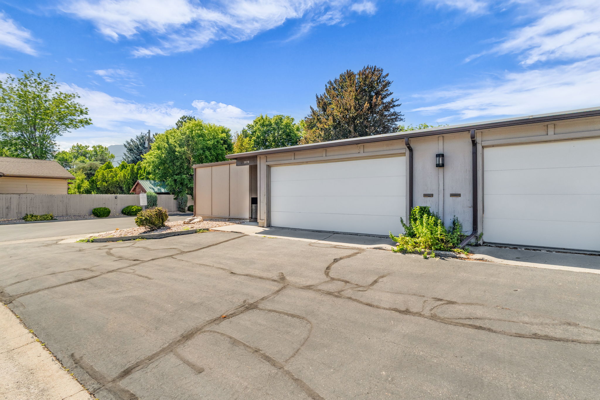 Attached garage with white panel doors and exterior wall sconce