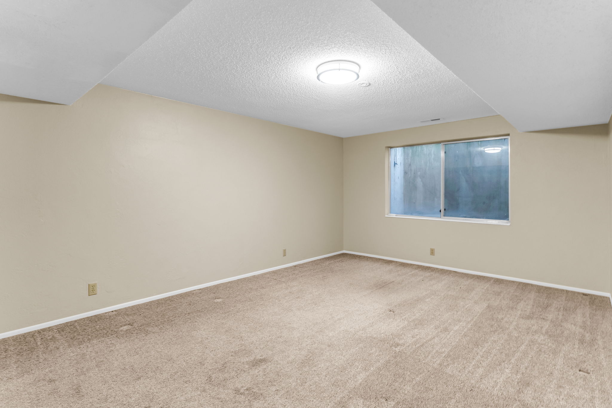 Carpeted room featuring a window and overhead lighting